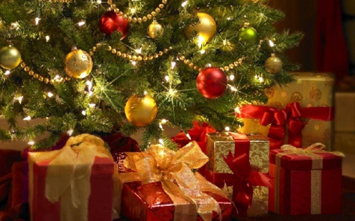 christmas laptop 桌布 壁紙 — 一棵溫暖照亮的聖誕樹，裝飾著紅色、金色和綠色的飾品以及閃爍的燈光，周圍環繞著包裝好的禮物。