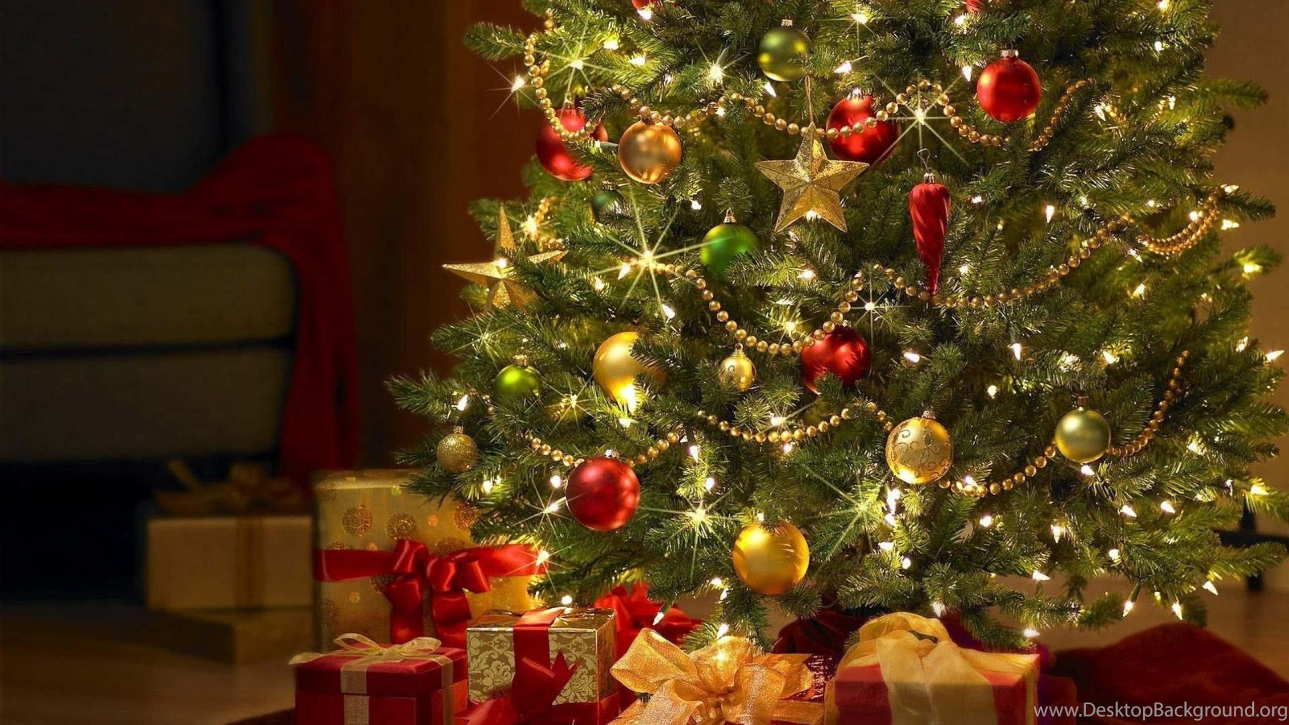 1920x1080 HD Christmas 桌布 壁紙 — 一棵溫暖照明的聖誕樹，裝飾著紅色、金色和綠色的飾品，閃爍著仙女燈，周圍環繞著包裝好的禮物。
