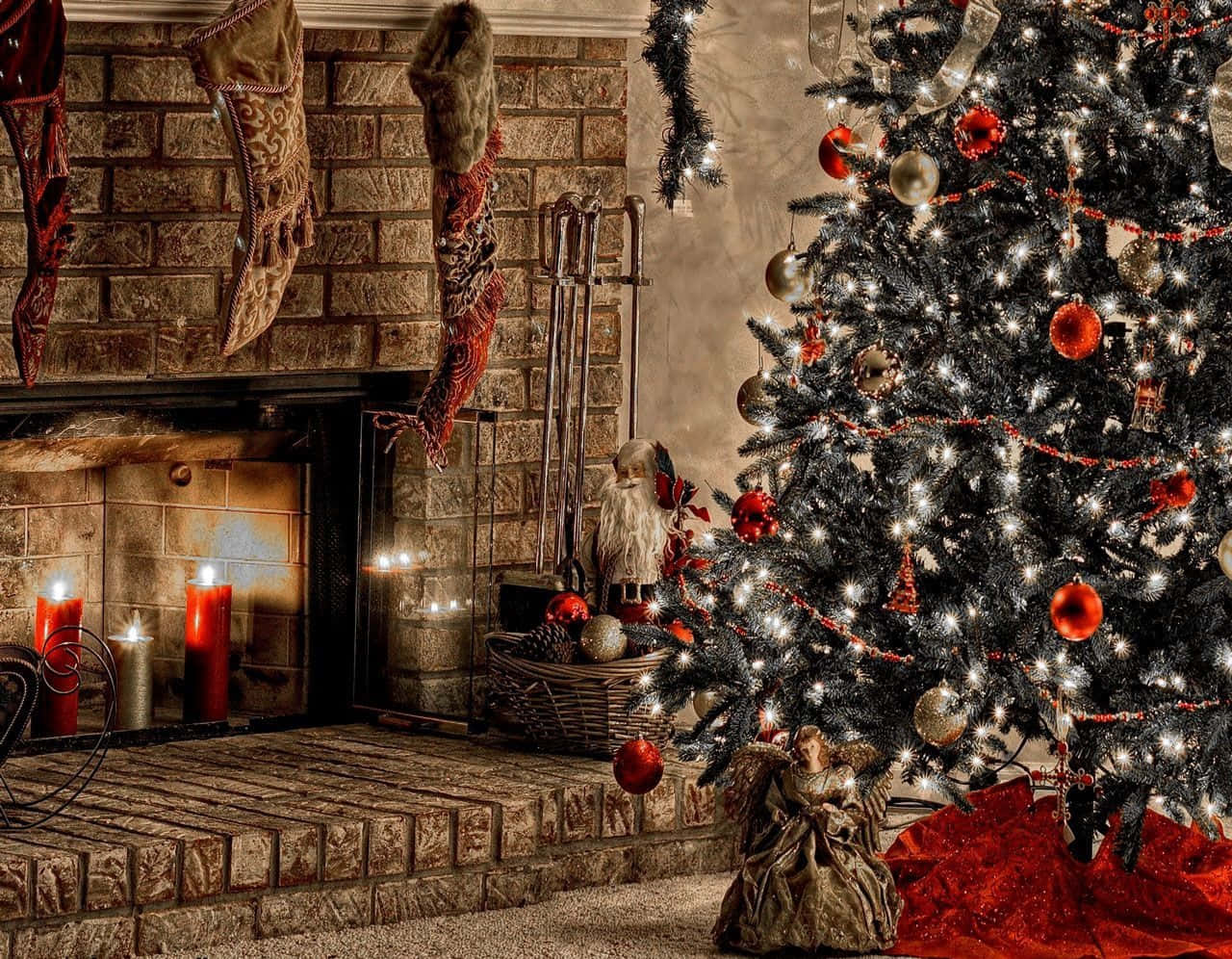 Christmas Fireplace 桌布 壁紙 — 一棵溫暖照明的聖誕樹，裝飾著紅色飾物和閃爍的燈光，旁邊是一個石壁爐，放著襪子和蠟燭。
