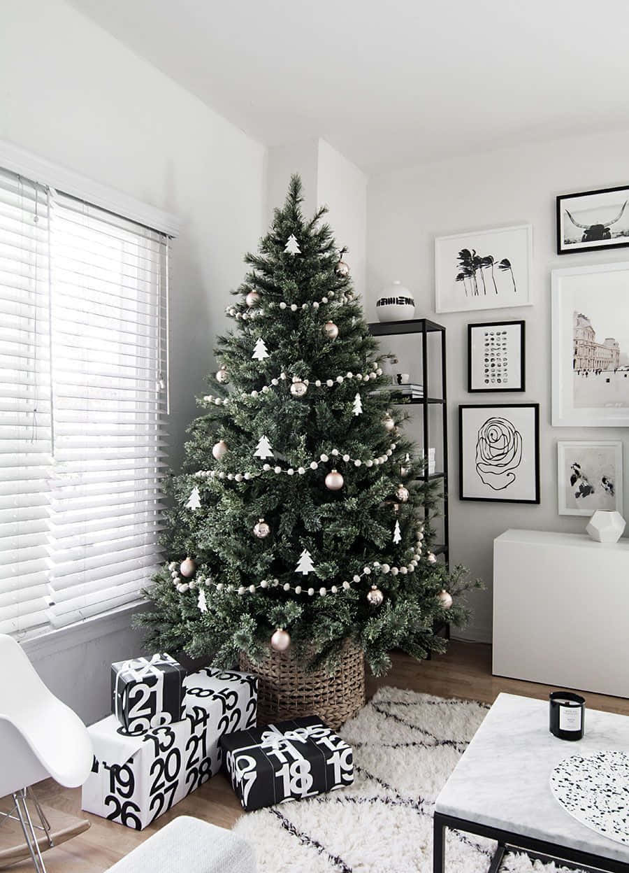 Aesthetic Christmas Tree 桌布 壁紙 — 一棵現代簡約風格的聖誕樹，裝飾著銀色和白色的飾品，矗立在一個明亮白色、黑白裝飾的房間裡。