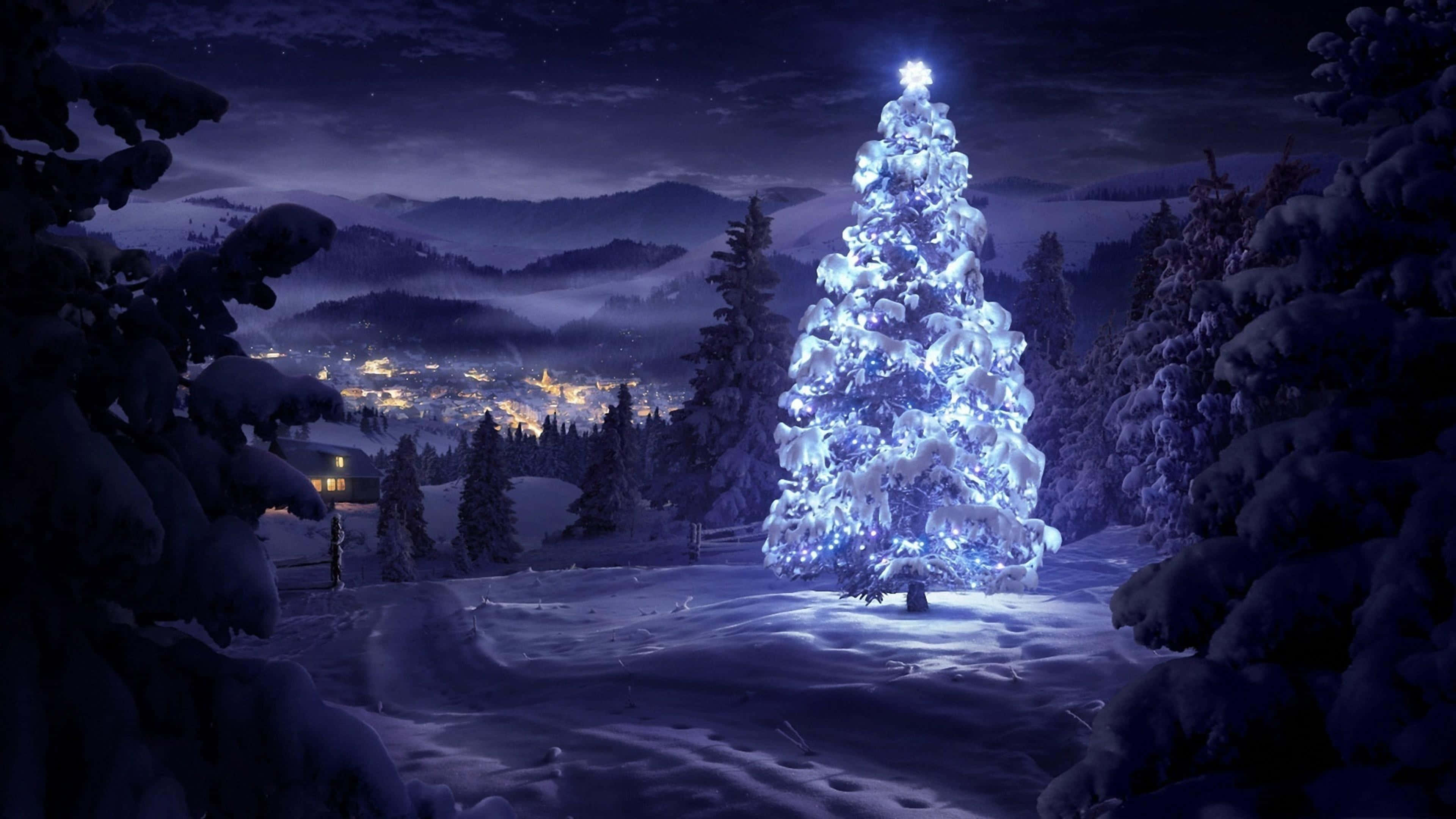 Microsoft Teams Christmas 桌布 壁紙 — 一棵發光的藍色聖誕樹矗立在雪白的冬夜中，照亮了霜凍的森林，下方遠處村莊的燈光閃爍。
