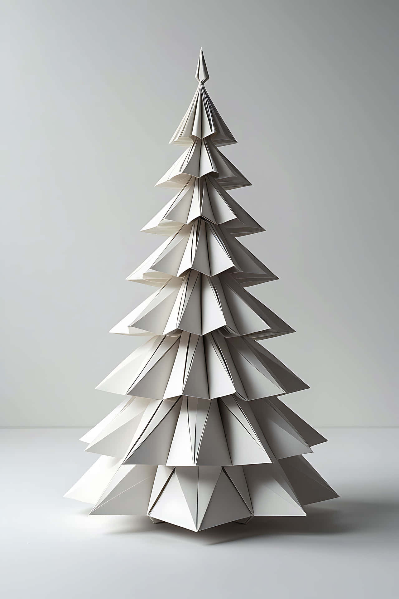 Origami christmas tree 壁紙 — 一棵簡約的白色紙摺紙聖誕樹在柔和的灰色工作室背景中高高聳立。