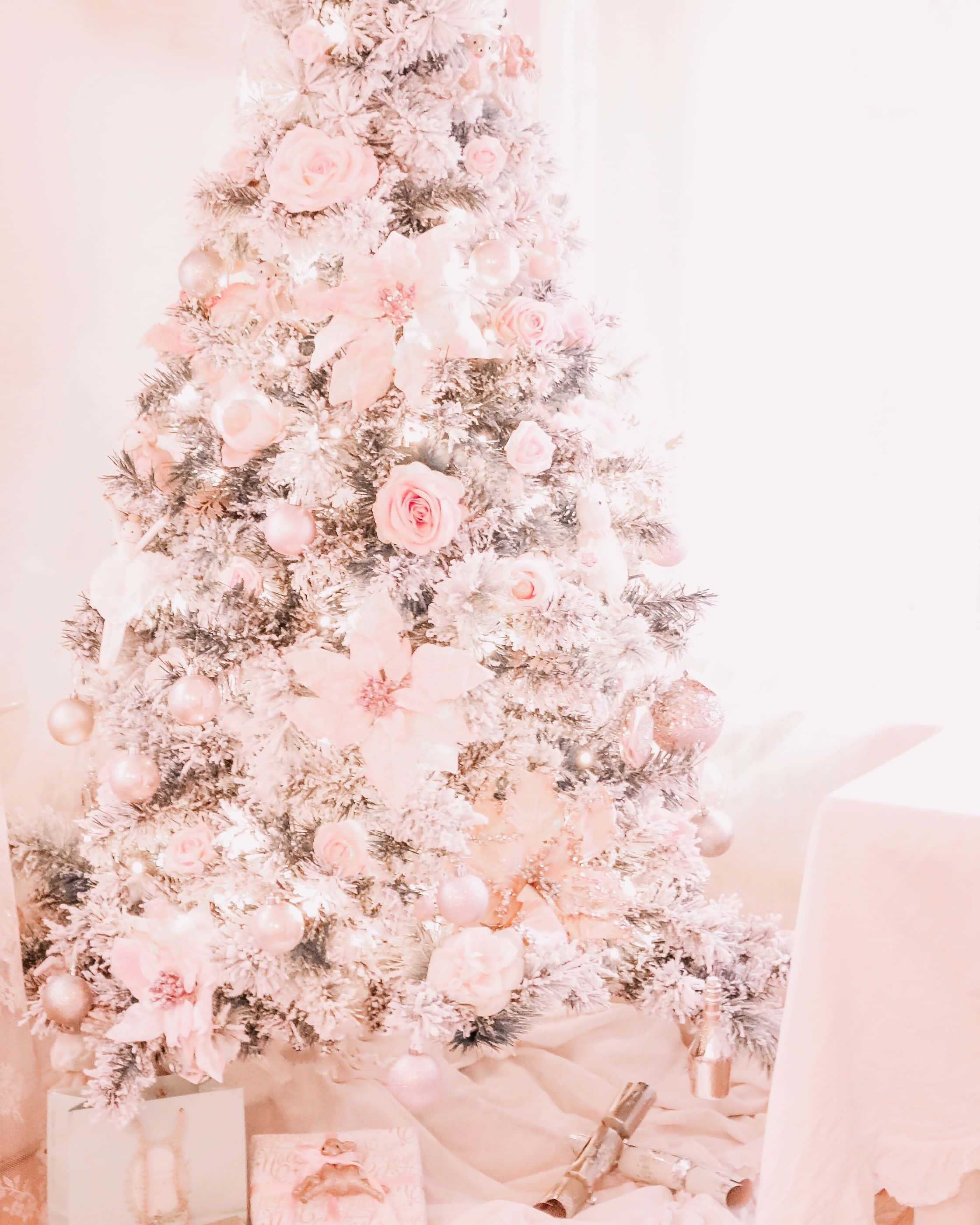 Pink Christmas Tree 桌布 壁紙 — 一棵結霜的聖誕樹，裝飾著柔和的粉紅玫瑰和閃閃發光的飾品，沐浴在溫暖的環境光中。