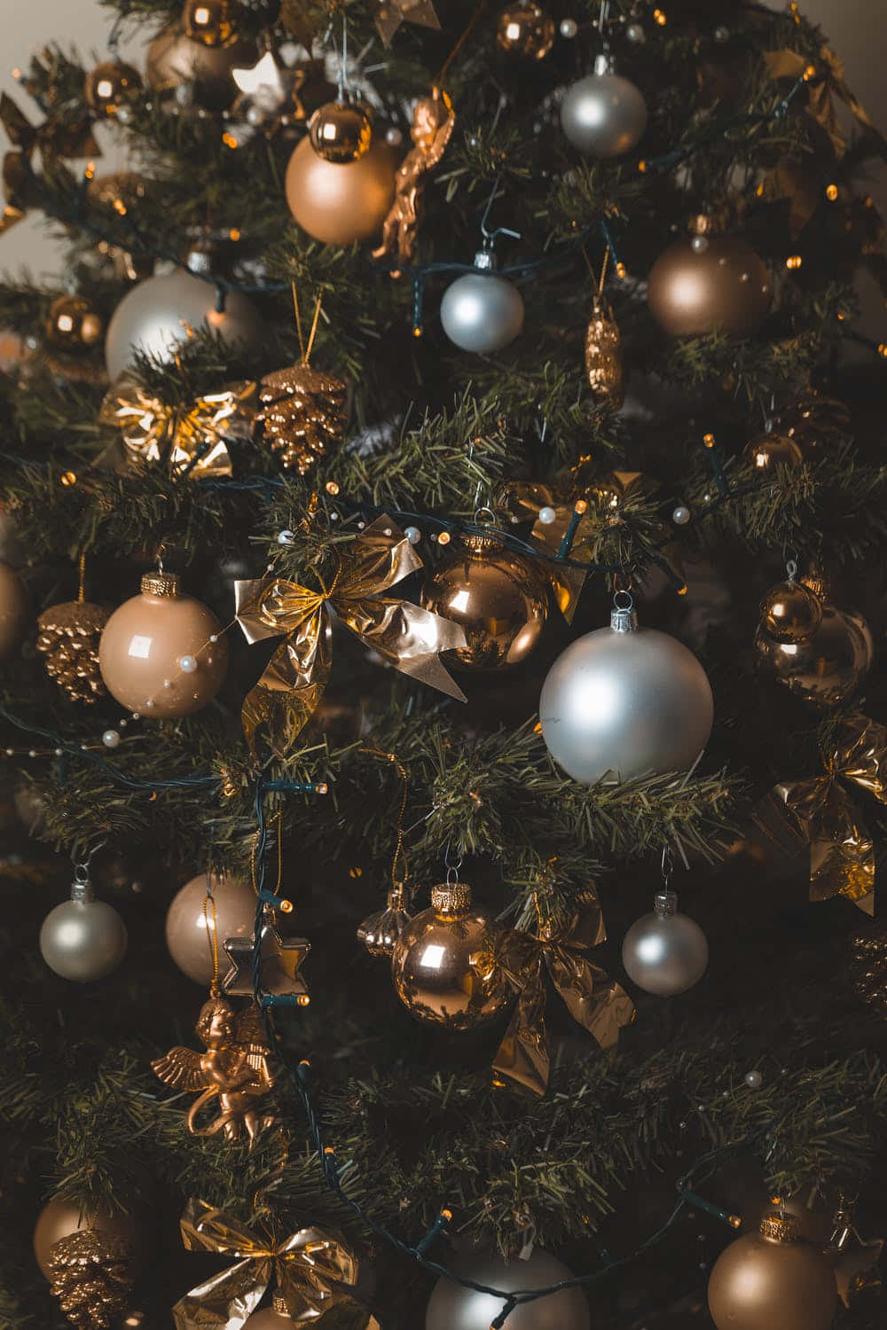 Aesthetic Christmas Tree 桌布 壁紙 — 一棵茂盛的綠色聖誕樹的特寫，裝飾著閃閃發光的金色和銀色飾品以及閃爍的仙女燈。