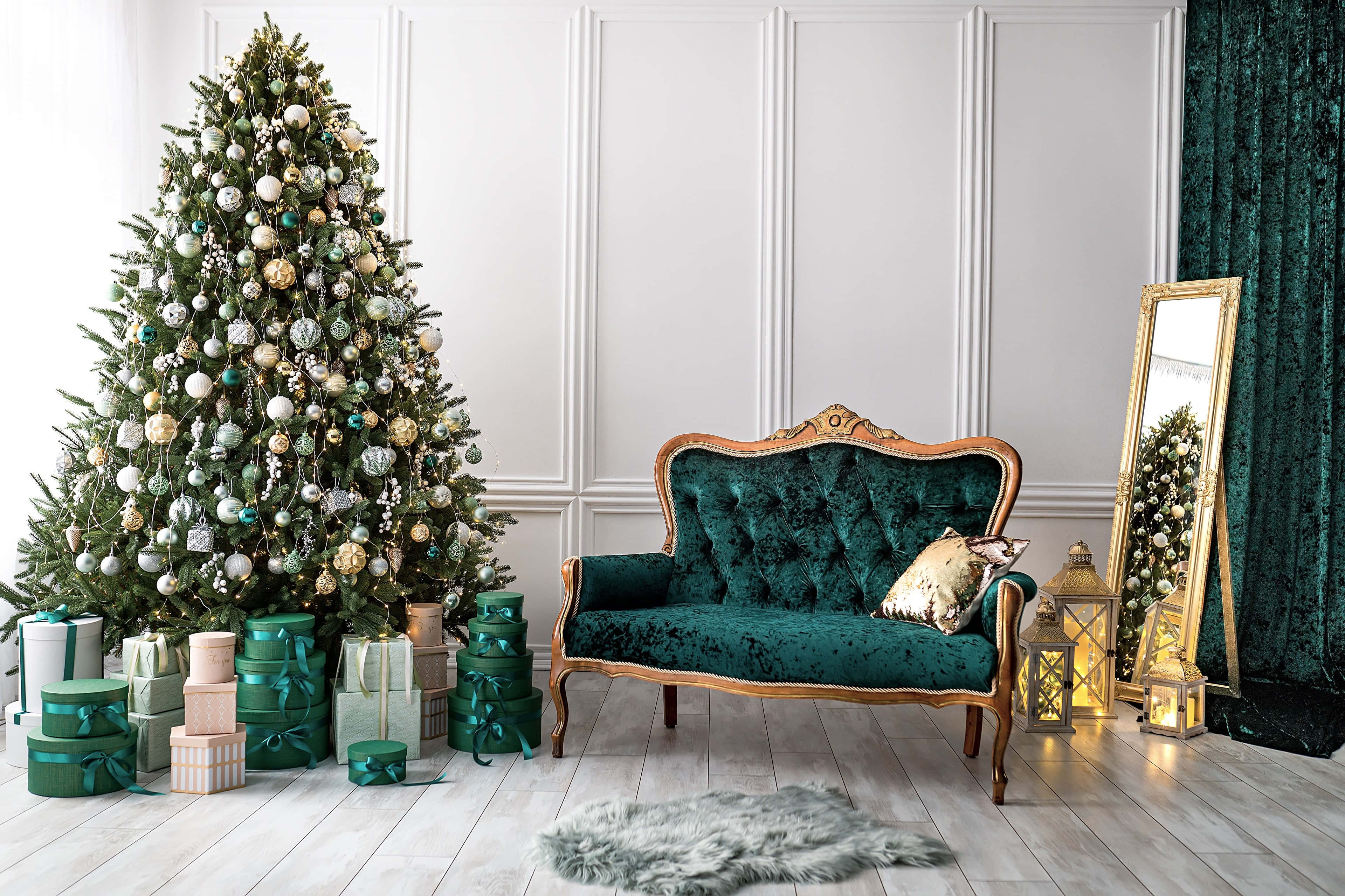 Christmas Living Room 桌布 壁紙 — 一棵裝飾華麗的聖誕樹矗立在一個明亮優雅的房間裡，旁邊是一張華麗的綠色天鵝絨沙發，房間裡還有禮物和燈籠。
