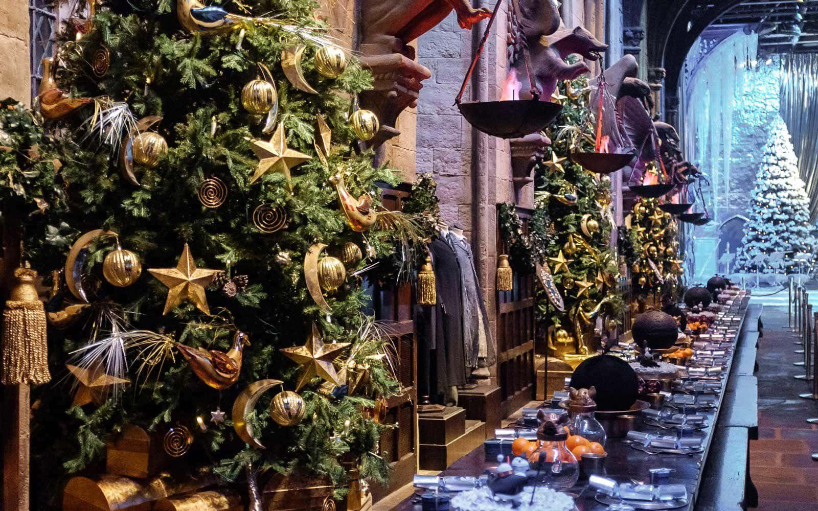 Harry Potter Christmas 桌布 壁紙 — 一棵裝飾著金色星星和飾品的大聖誕樹，矗立在石牆商店中一個節日魔法商品的展示旁邊。