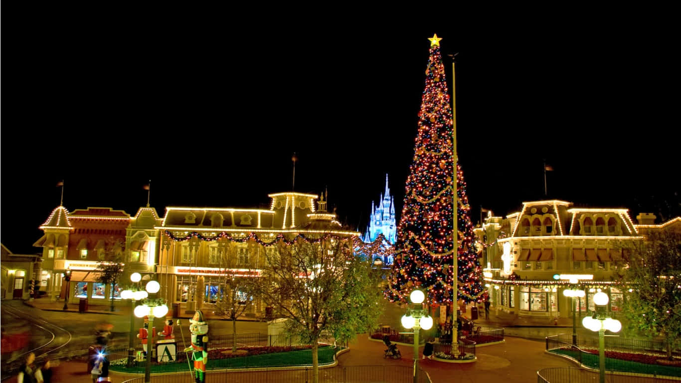 1366x768 Disney 桌布 壁紙 — 一棵高聳的聖誕樹裝飾著閃爍的燈光，在夜晚自豪地矗立在節日氣氛濃厚、燈火輝煌的迪士尼城堡前。