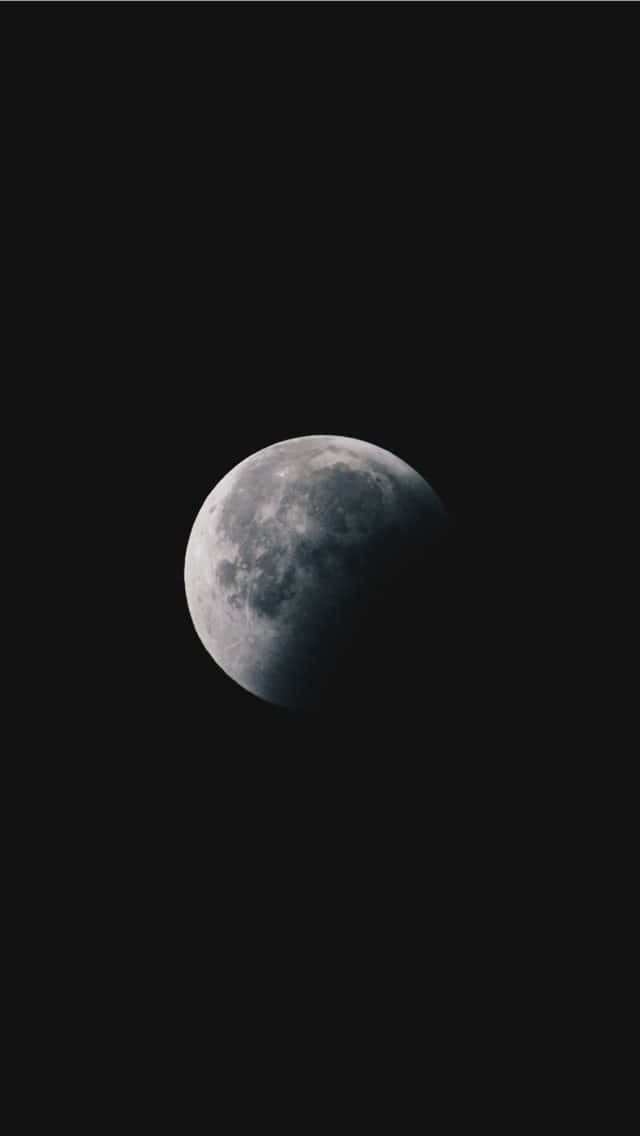 Moon iPhone 桌布 壁紙 — 一次戲劇性的月食顯示半個月亮在漆黑天空中照亮。