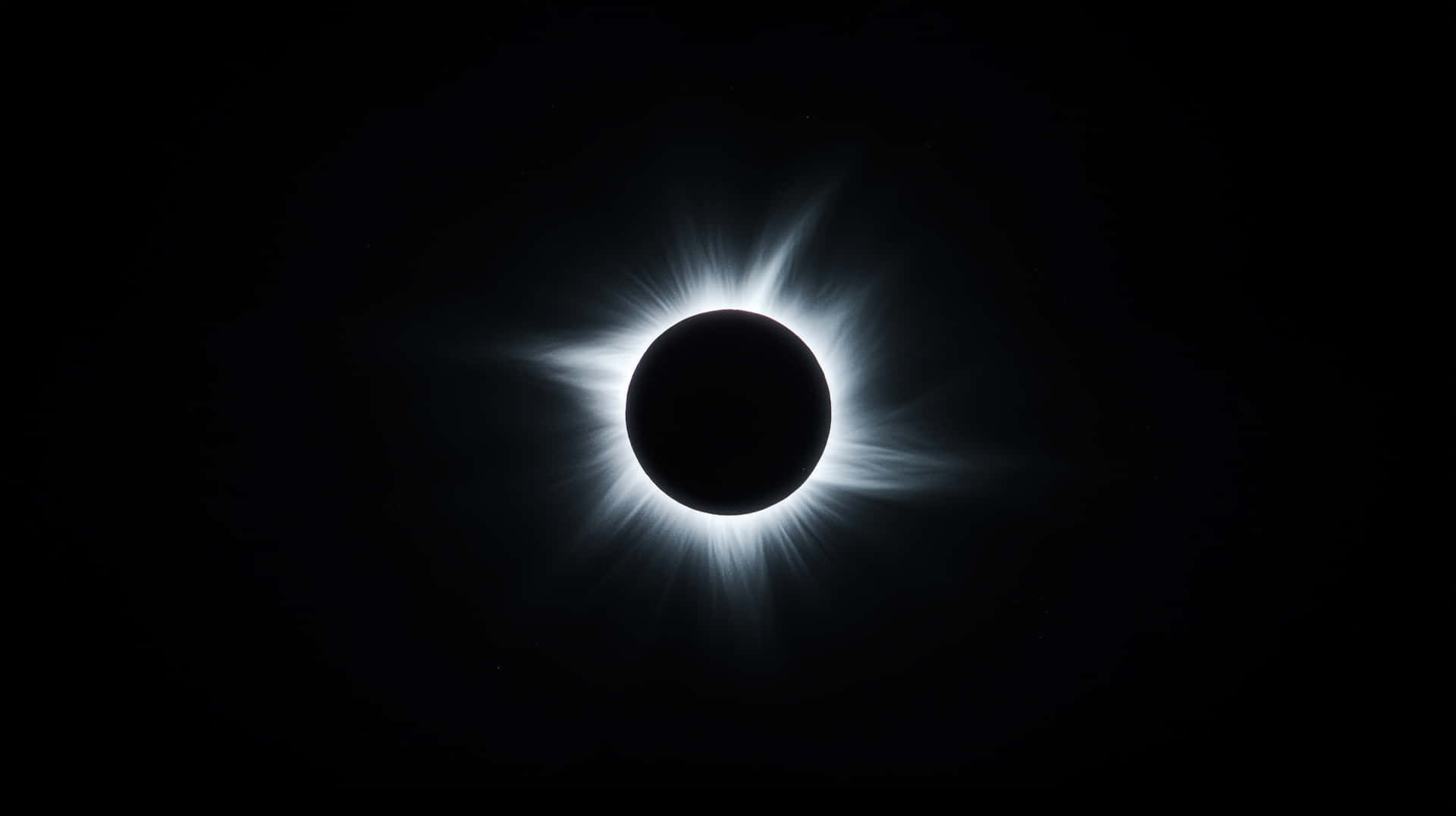 A stunning image of a total solar eclipse, showing the moon completely covering the sun 壁紙 — 一次日全食，明亮的白色日冕從黑暗的太陽向黑色天空輻射。