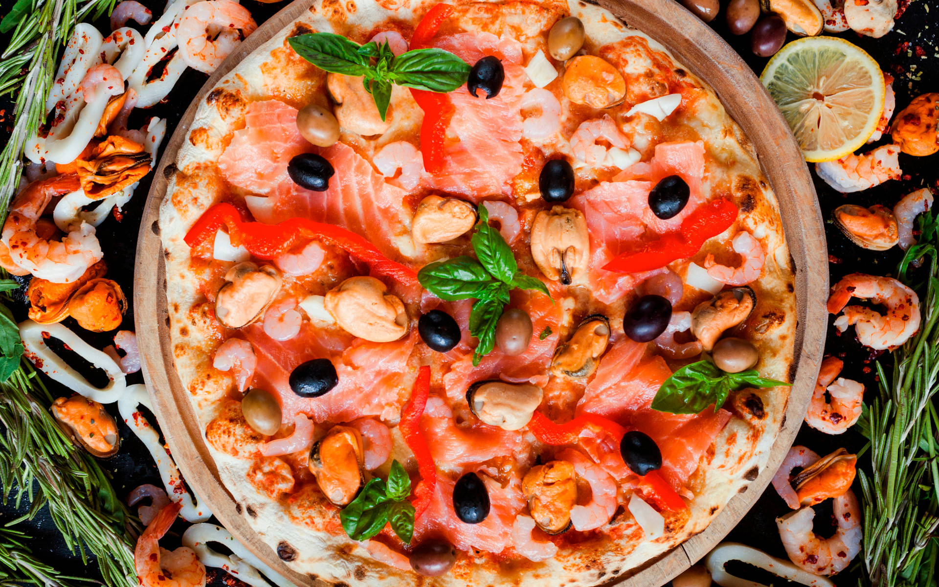 Pizza 桌布 壁紙 — 一款充滿活力的海鮮披薩，上面鋪有鮭魚、蝦、貽貝、橄欖和羅勒，周圍環繞著新鮮香草和檸檬。