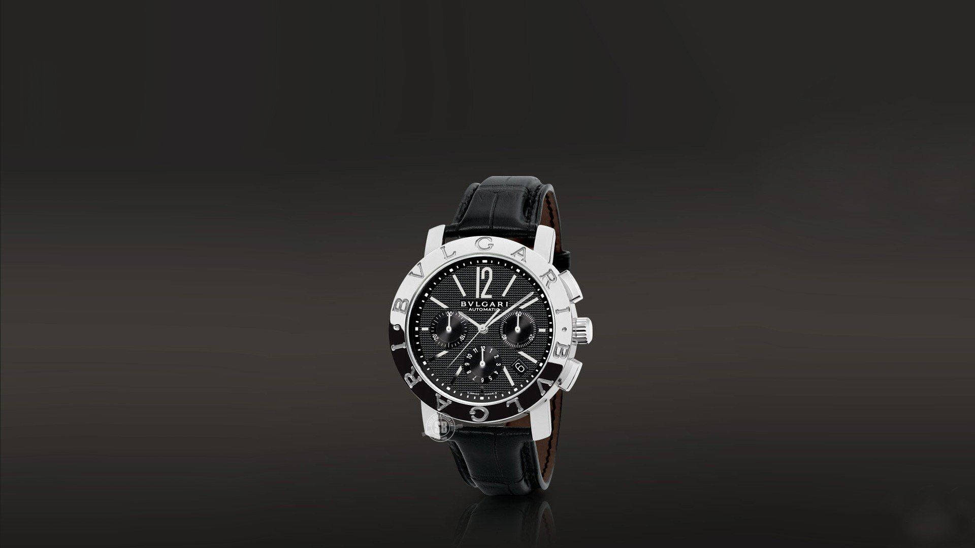 Bvlgari 桌布 壁紙 — 一款時尚的Bvlgari計時碼錶，黑色錶盤和皮革錶帶，在深色漸變背景中央展示。