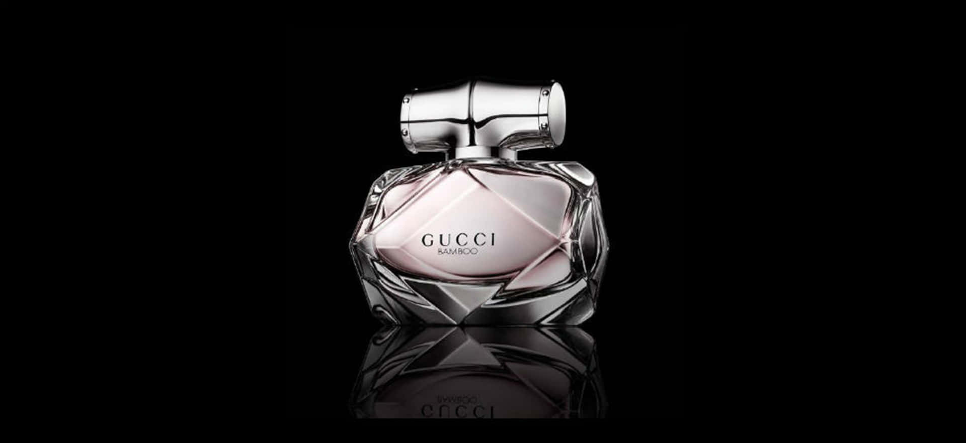 Gucci 桌布 壁紙 — 一款時尚的Gucci Bamboo香水瓶，採用多面玻璃設計和銀色瓶蓋，在黑色背景上柔和發光。