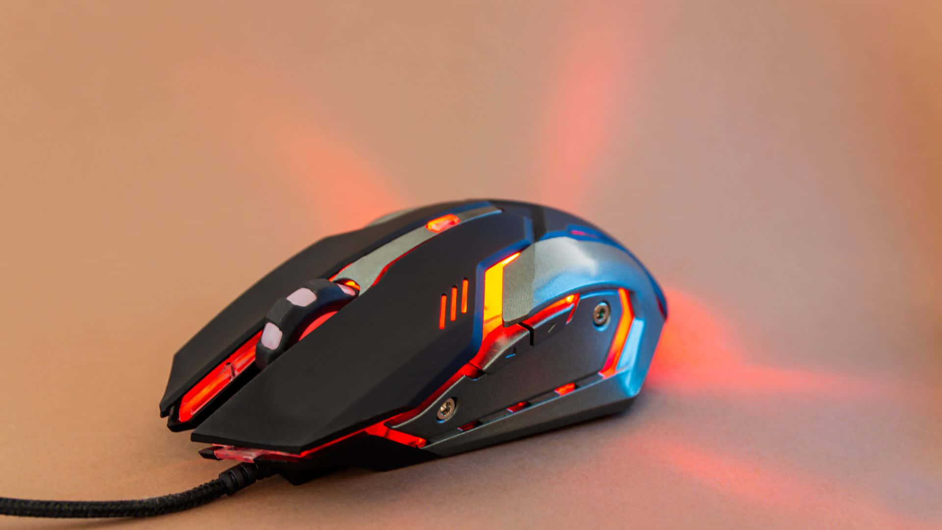 Gaming Mice 桌布 壁紙 — 一款時尚的遊戲滑鼠，帶有發光的紅色和藍色燈光，放置在溫暖的米色表面上，投射出柔和多彩的反射。