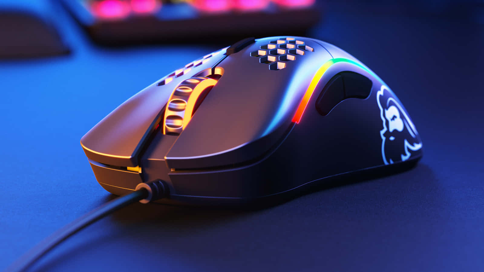 Gaming Mice 桌布 壁紙 — 一款時尚的遊戲滑鼠，帶有鮮豔的彩虹RGB燈光，放置在深藍色桌面上，在戲劇性的藍色環境燈光下。