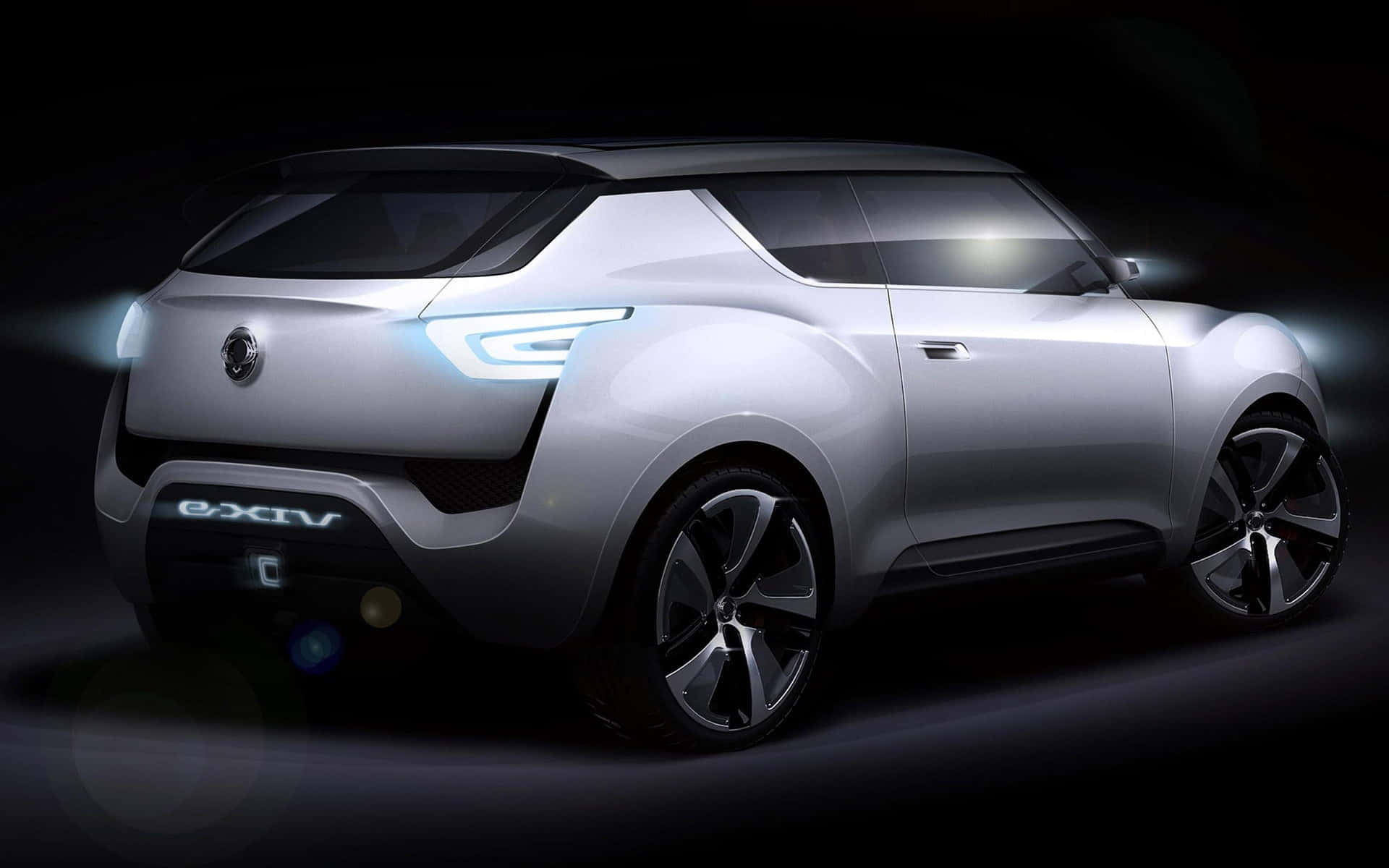 Ssangyong 桌布 壁紙 — 一款時尚的銀色概念SUV在黑暗的攝影棚背景下散發出未來感的藍色光芒。