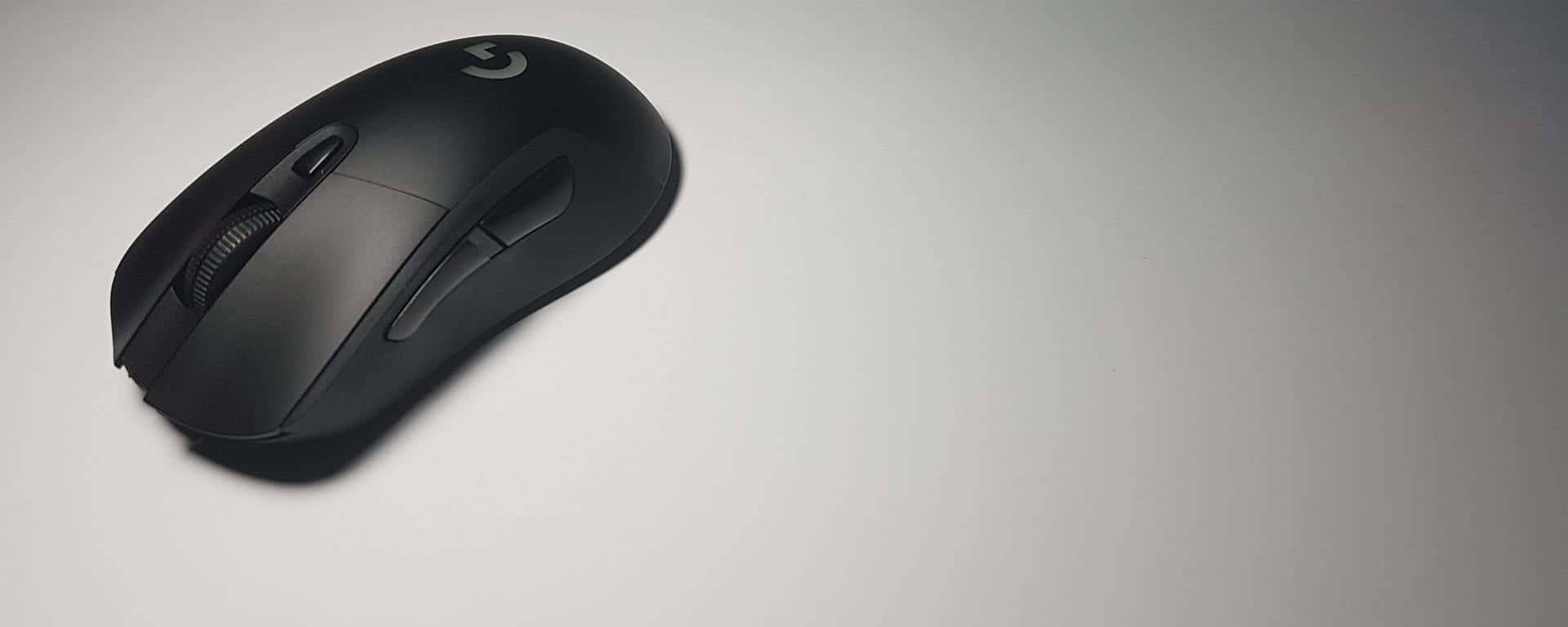 Gaming Mouse 桌布 壁紙 — 一款時尚的黑色Logitech遊戲滑鼠放置在簡約淺灰色表面上，帶有柔和陰影。