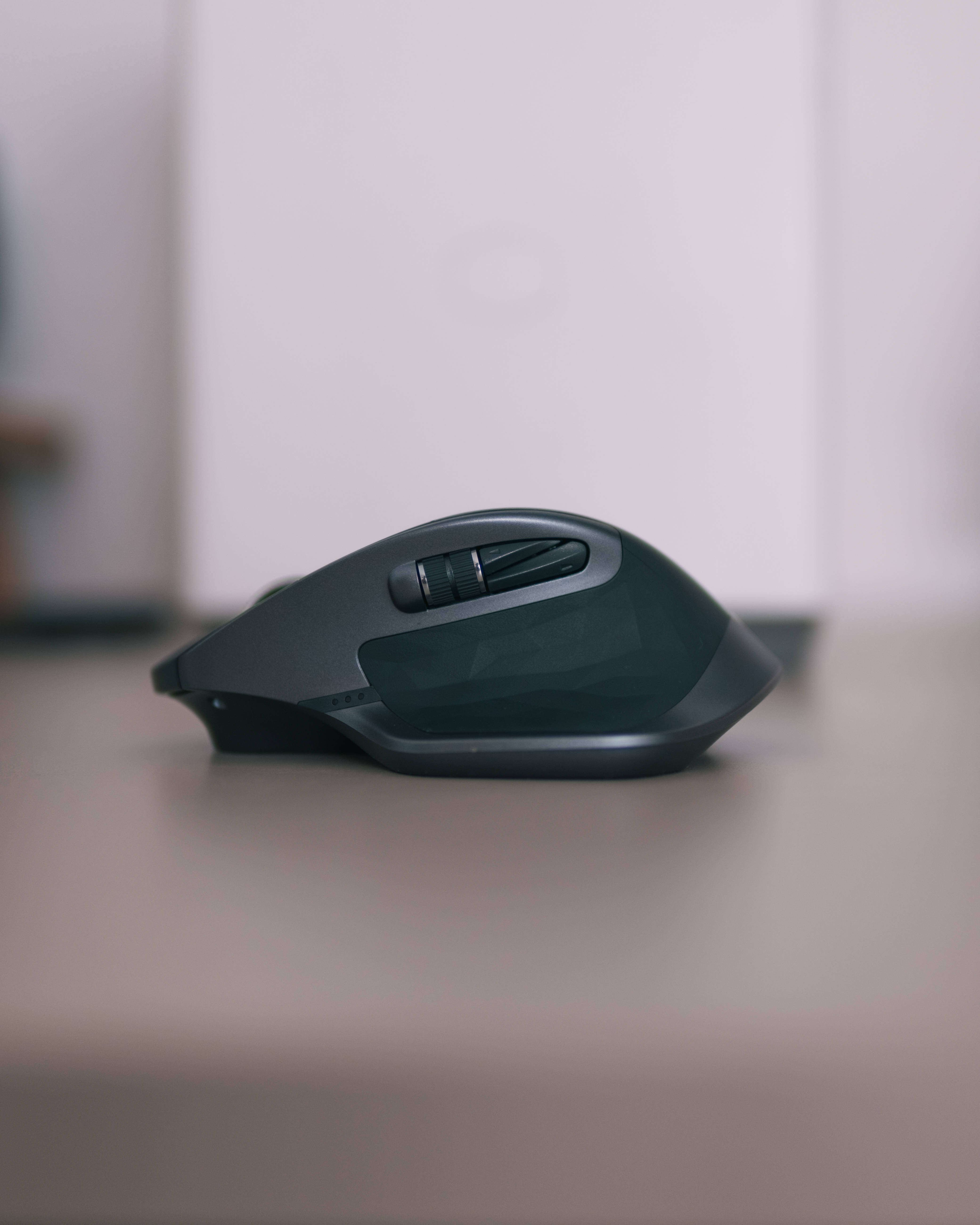 Mouse 桌布 壁紙 — 一款時尚的黑色人體工學電腦滑鼠放置在簡約的辦公桌上，背景柔和模糊。
