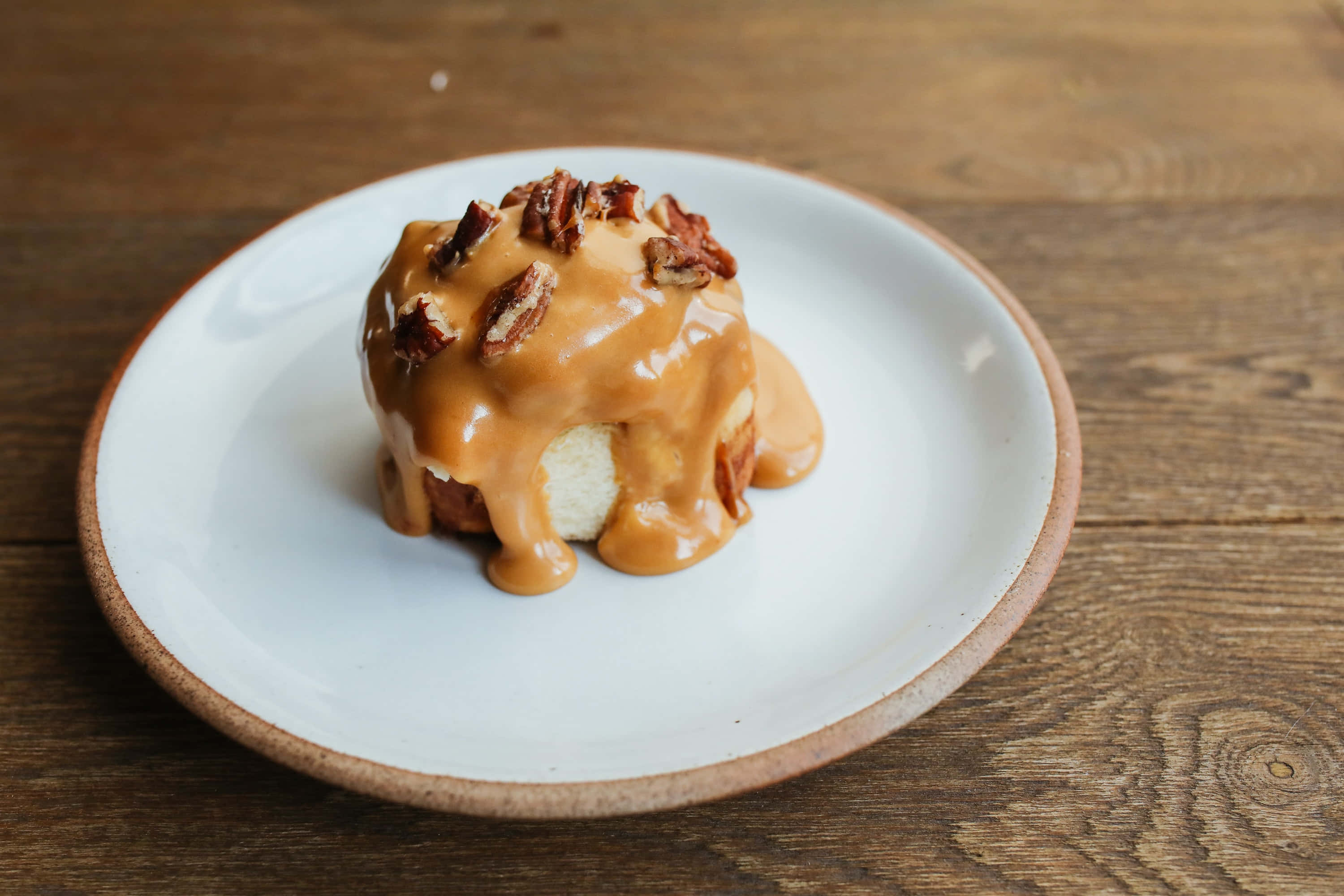 Caramel 桌布 壁紙 — 一款淋上焦糖、撒上胡桃的甜點，放在白色盤子上，置於鄉村風木桌上。