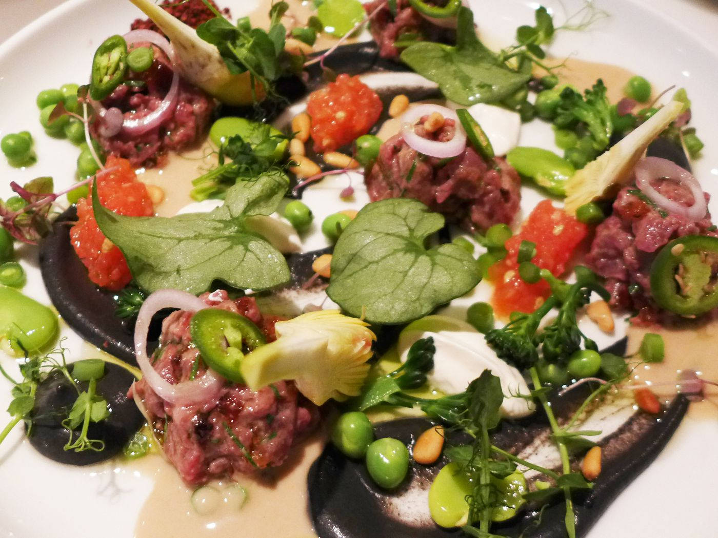 meat 桌布 壁紙 — 一款美食級牛肉他他菜餚，在白盤上以微型蔬菜、豌豆、墨西哥辣椒和奶油醬汁藝術性地擺盤。