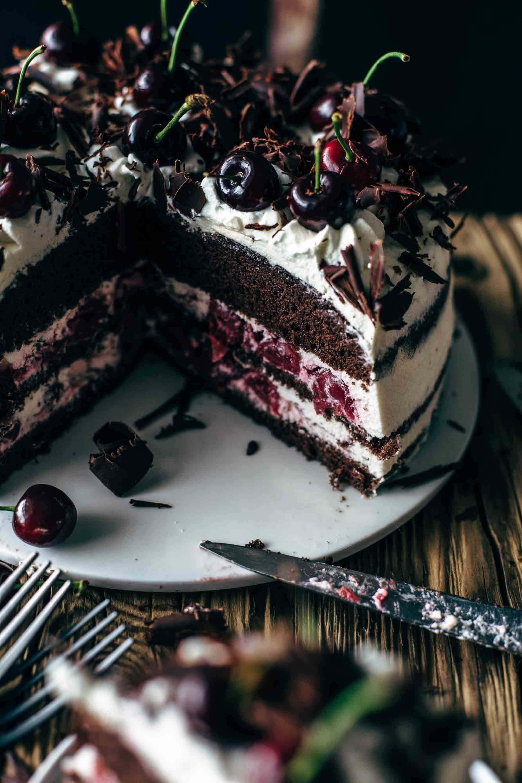 Black Forest Cake 桌布 壁紙 — 一款頹廢的黑森林蛋糕，層層疊疊的巧克力海綿蛋糕、櫻桃餡料和鮮奶油，上面鋪滿新鮮櫻桃和巧克力碎片。