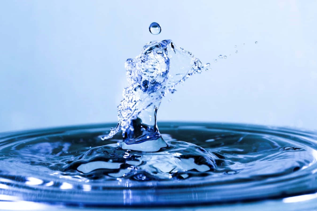 Water Drop 桌布 壁紙 — 一滴完美的藍色水珠在慢動作中向上飛濺，背景是柔和的藍色漸變。