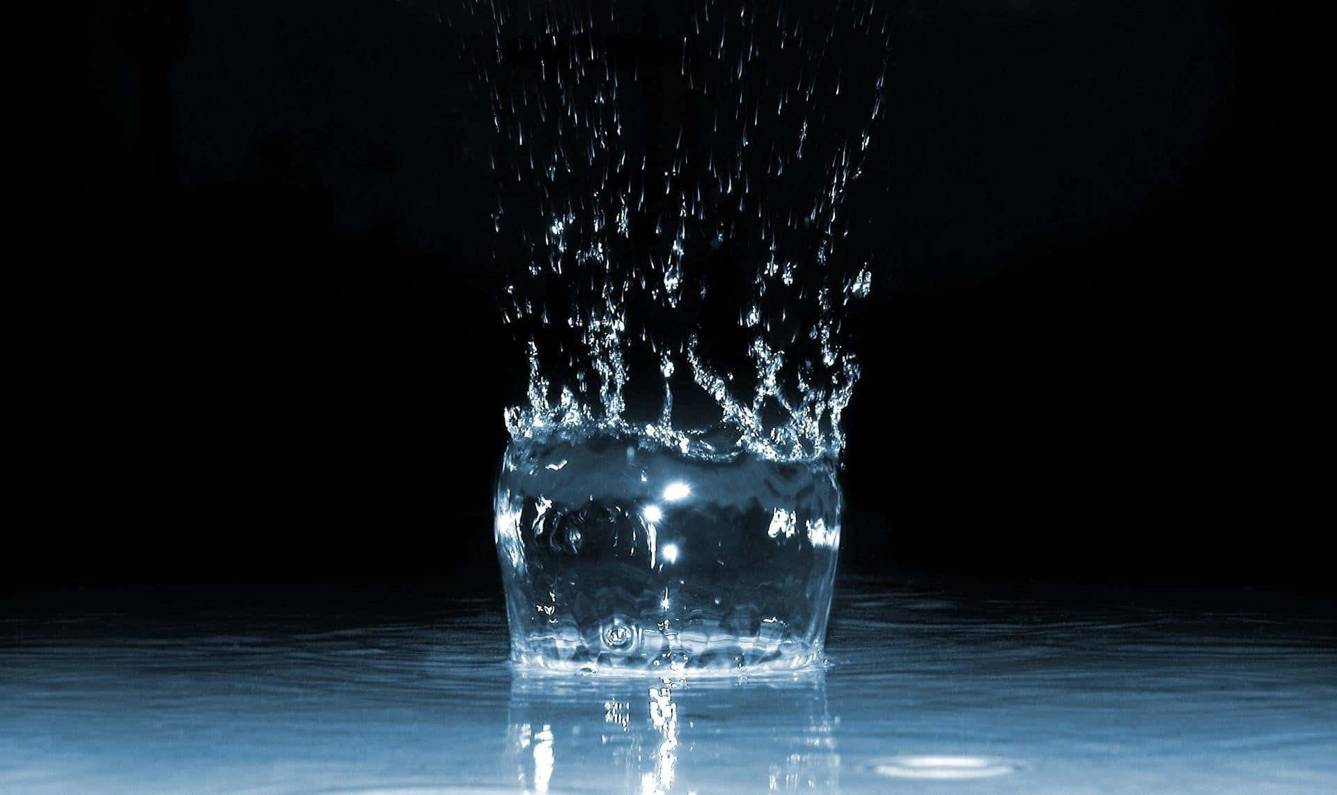 Water Droplet 桌布 壁紙 — 一滴水在黑色背景上伴隨藍色反射碎裂成閃爍的水滴。