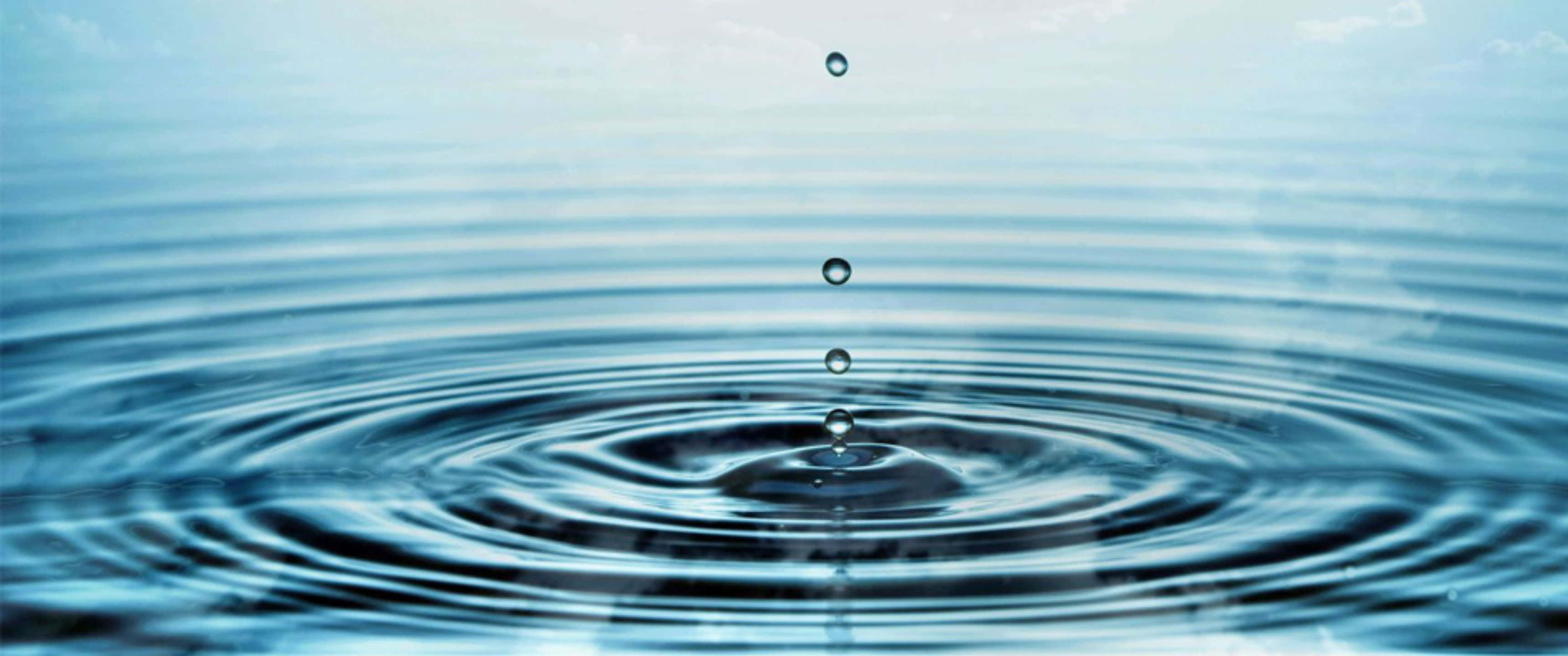 水 桌布 壁紙 — 一滴水滴穿過空氣落下，在平靜的藍色表面上形成完美的同心漣漪，在柔和日光下。