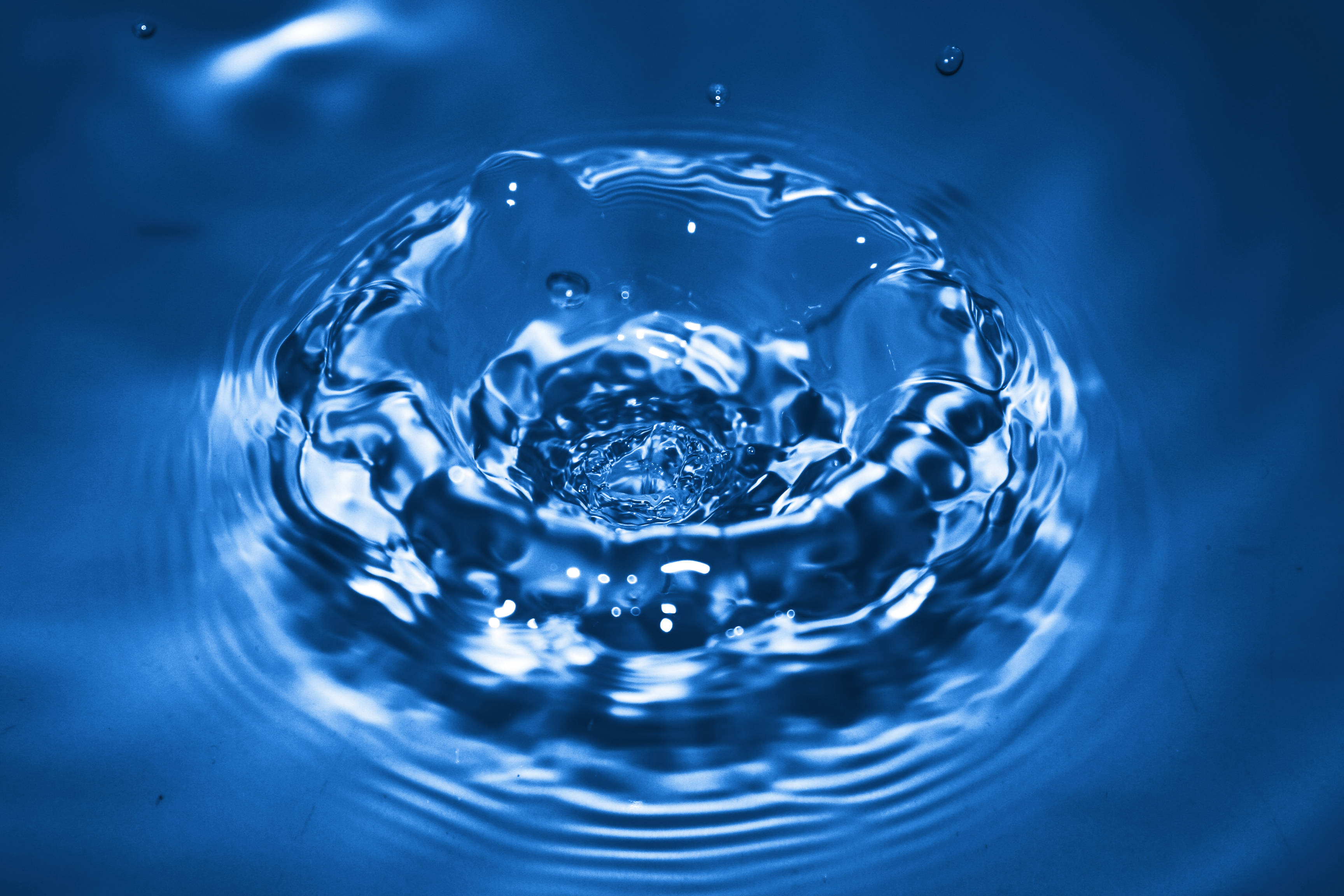 Water Splash 桌布 壁紙 — 一滴水珠在深藍色液體中產生漣漪，帶有閃爍高光的特寫。