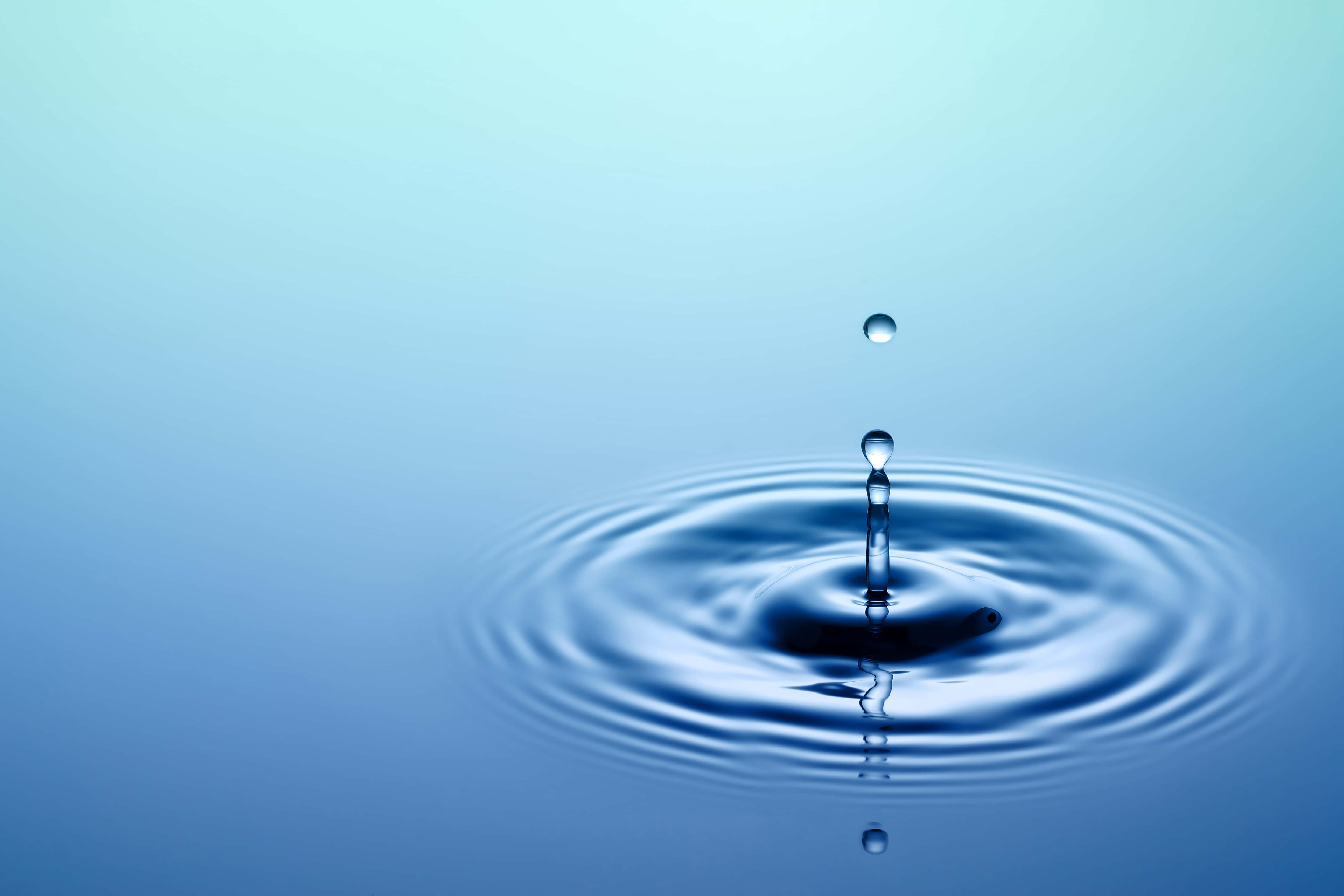 Hydration 桌布 壁紙 — 一滴水珠懸浮在平靜的藍色水面上，形成完美的同心漣漪和倒影。