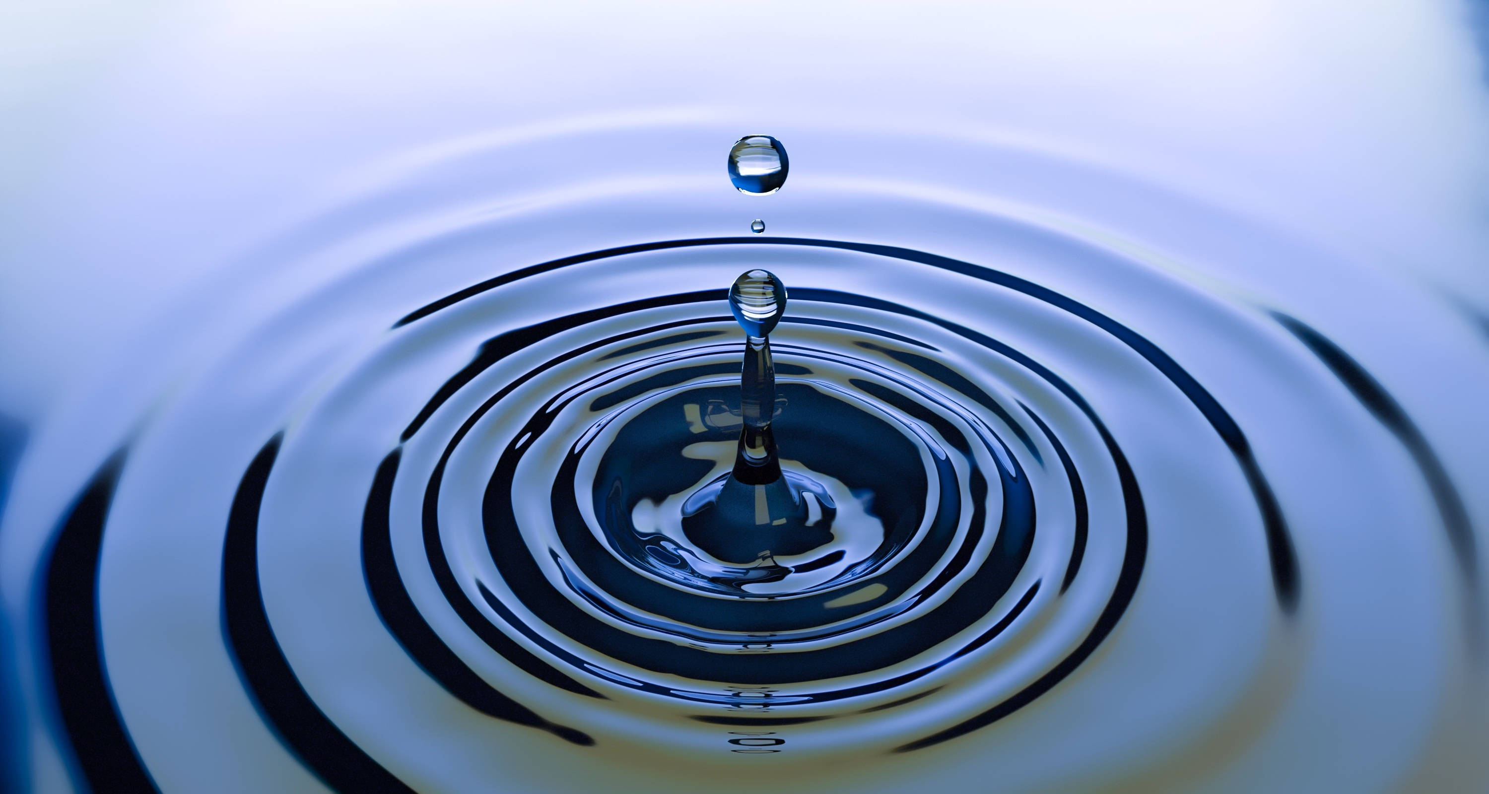 Cool Water 桌布 壁紙 — 一滴水珠懸浮在表面上，以清涼的藍色調形成完美的同心漣漪。