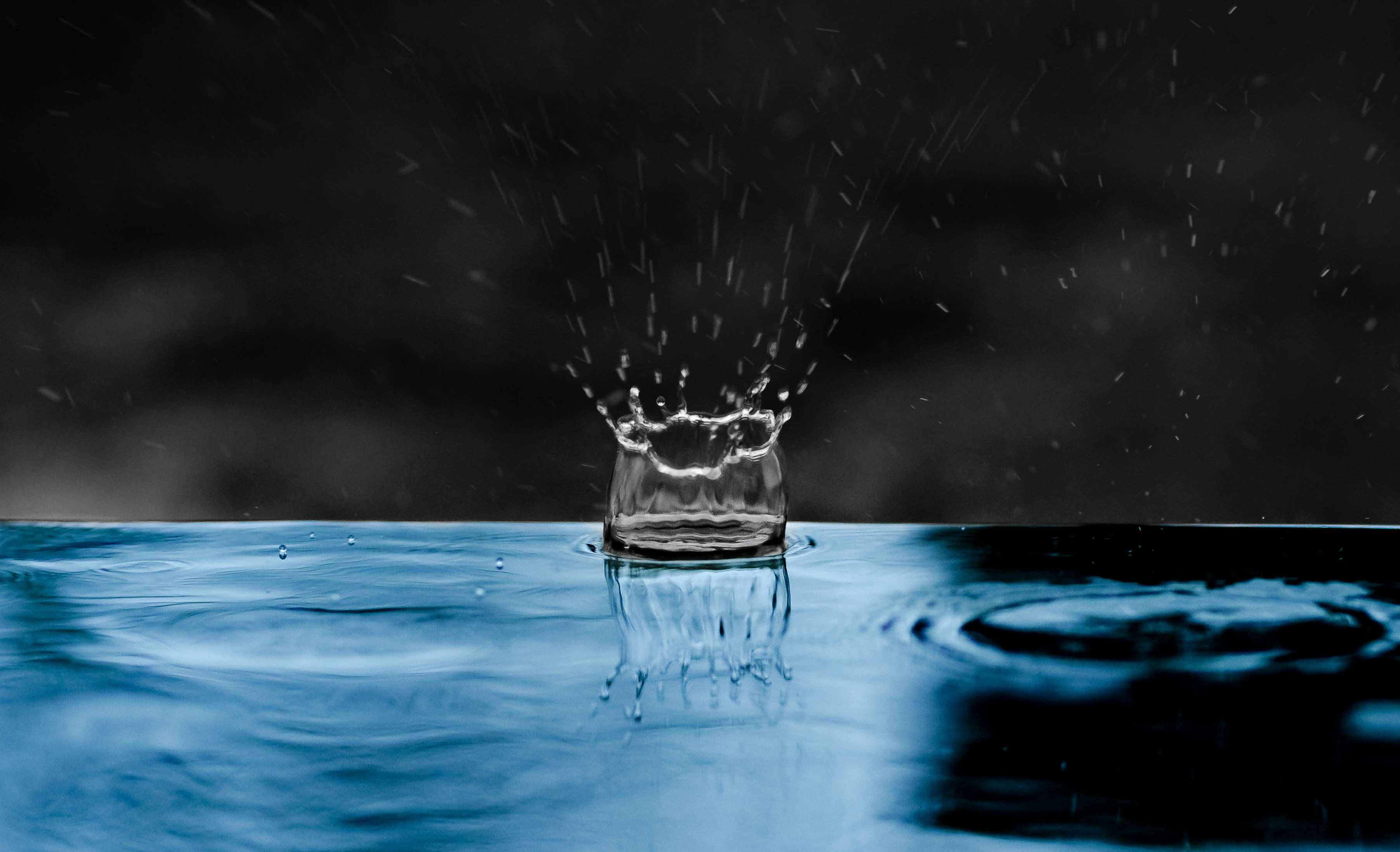 水 桌布 壁紙 — 一滴雨滴在深色背景的平靜藍色水面上形成完美的水花皇冠。