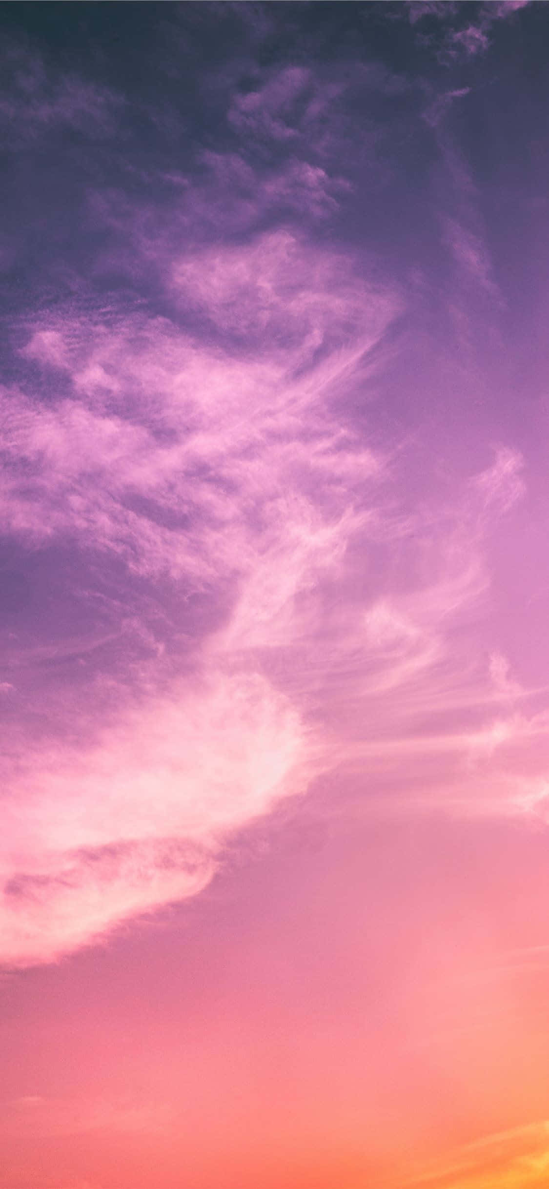 Purple Clouds 桌布 壁紙 — 一片充滿活力的天空從深紫色過渡到柔和的粉紅色和溫暖的橙色，薄雲在地平線上飄移。