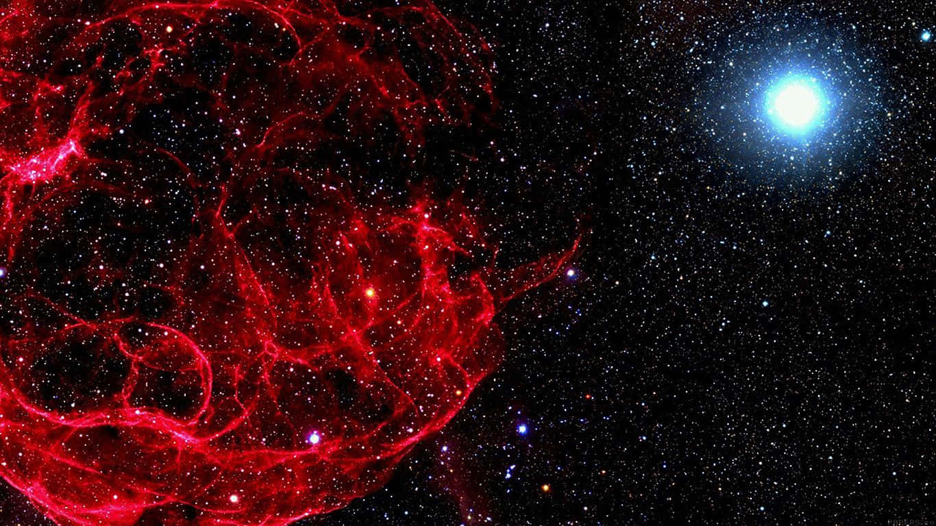 星雲 桌布 壁紙 — 一片充滿活力的紅色星雲在星場中旋轉，遠處有一顆明亮的藍色星星閃耀。