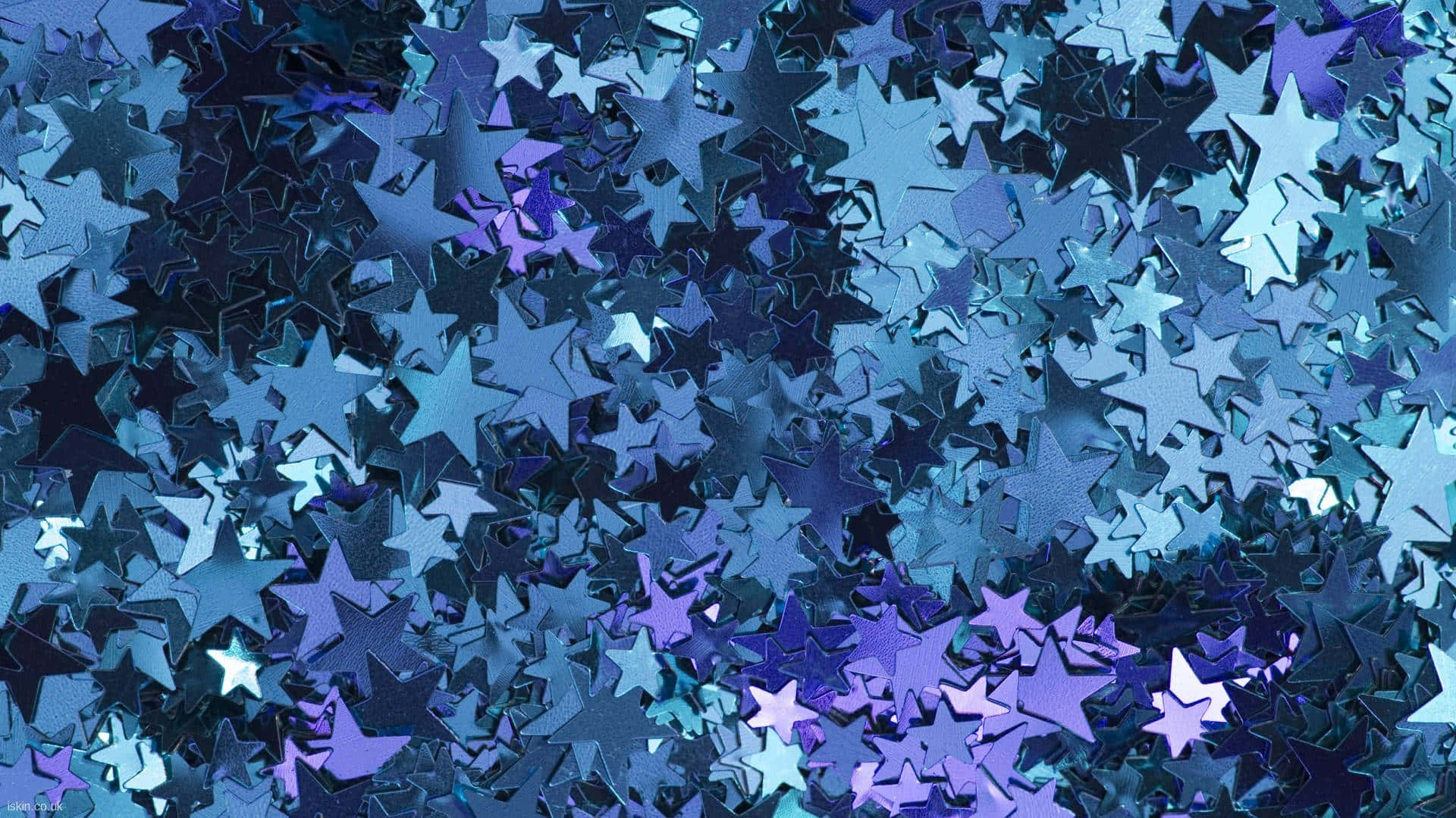 Blue Sparkle 桌布 壁紙 — 一片密集的金屬藍色和紫色星形紙碎，具有反光表面和不同尺寸。