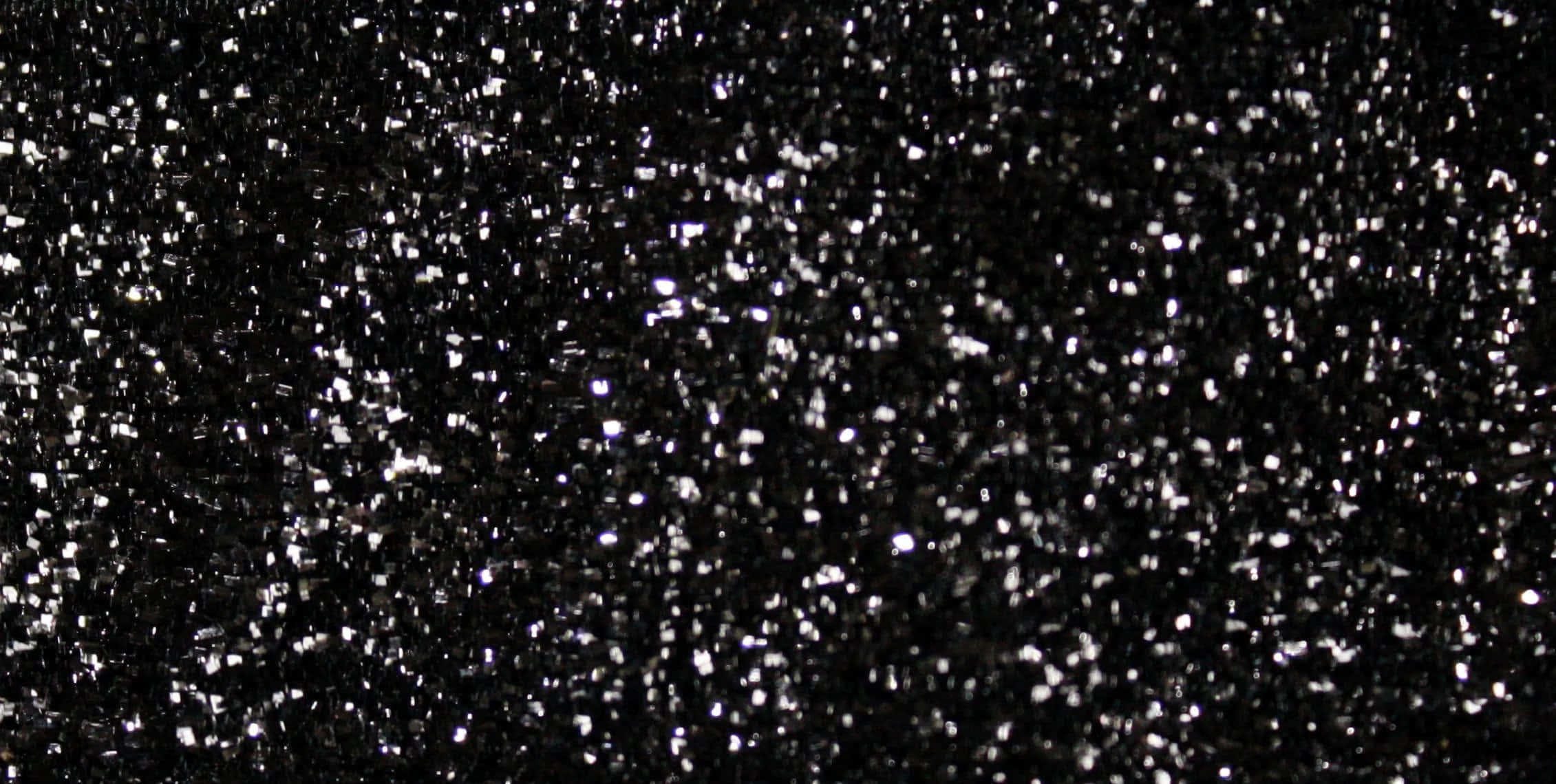 Black Glitter 桌布 壁紙 — 一片密集的閃爍銀色亮粉顆粒散落在深黑色背景上。