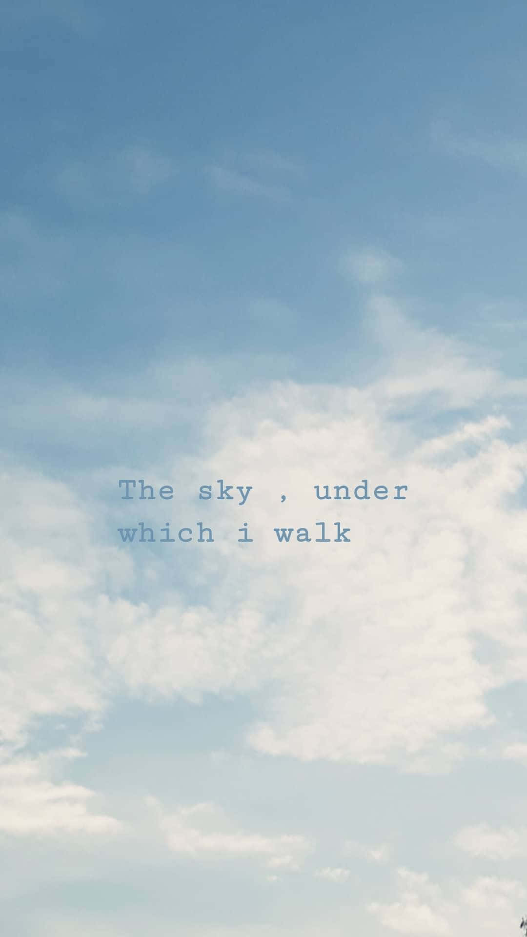 Aesthetic Sky 桌布 壁紙 — 一片寧靜的天空，帶有柔軟的白雲和淺藍色調，以微妙的字體顯示文字「The sky, under which i walk」。