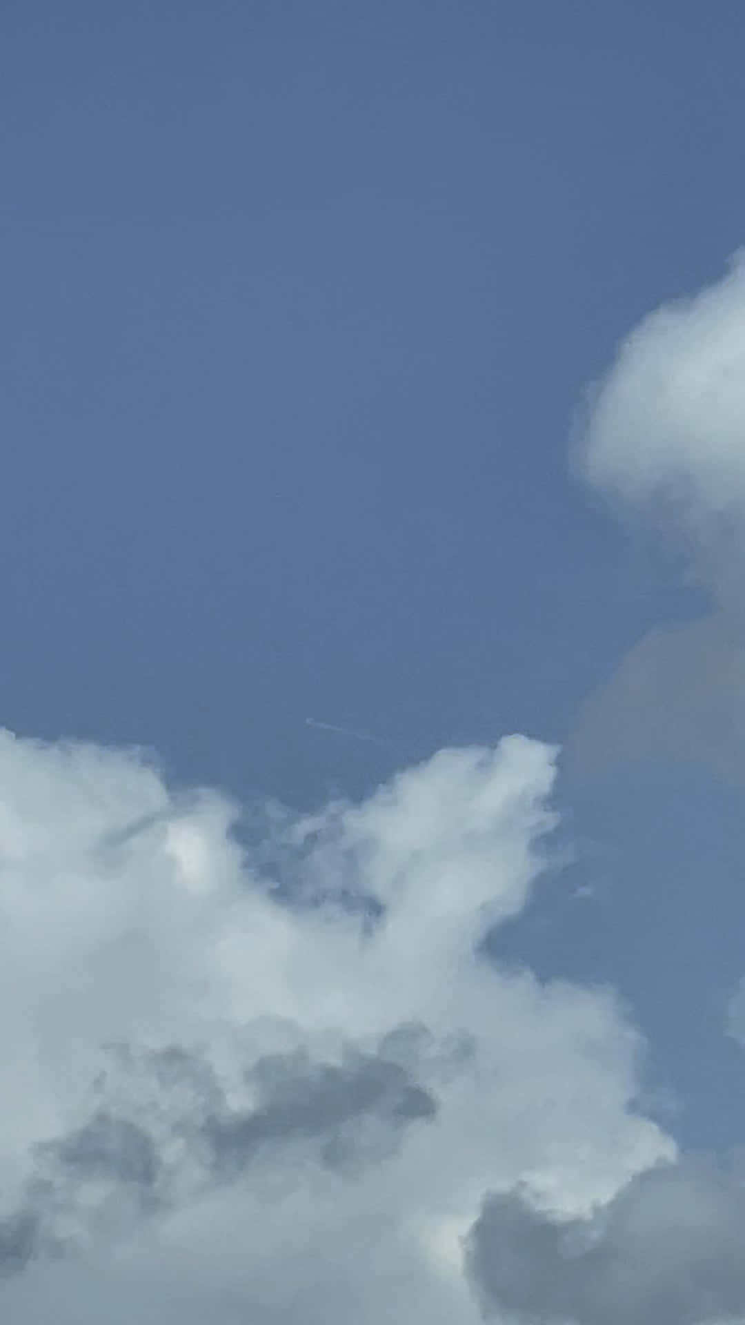 Clouds Aesthetic Tumblr 桌布 壁紙 — 一片寧靜的藍天，有蓬鬆的白雲，遠處有一架飛機留下一條細細的凝結尾跡。