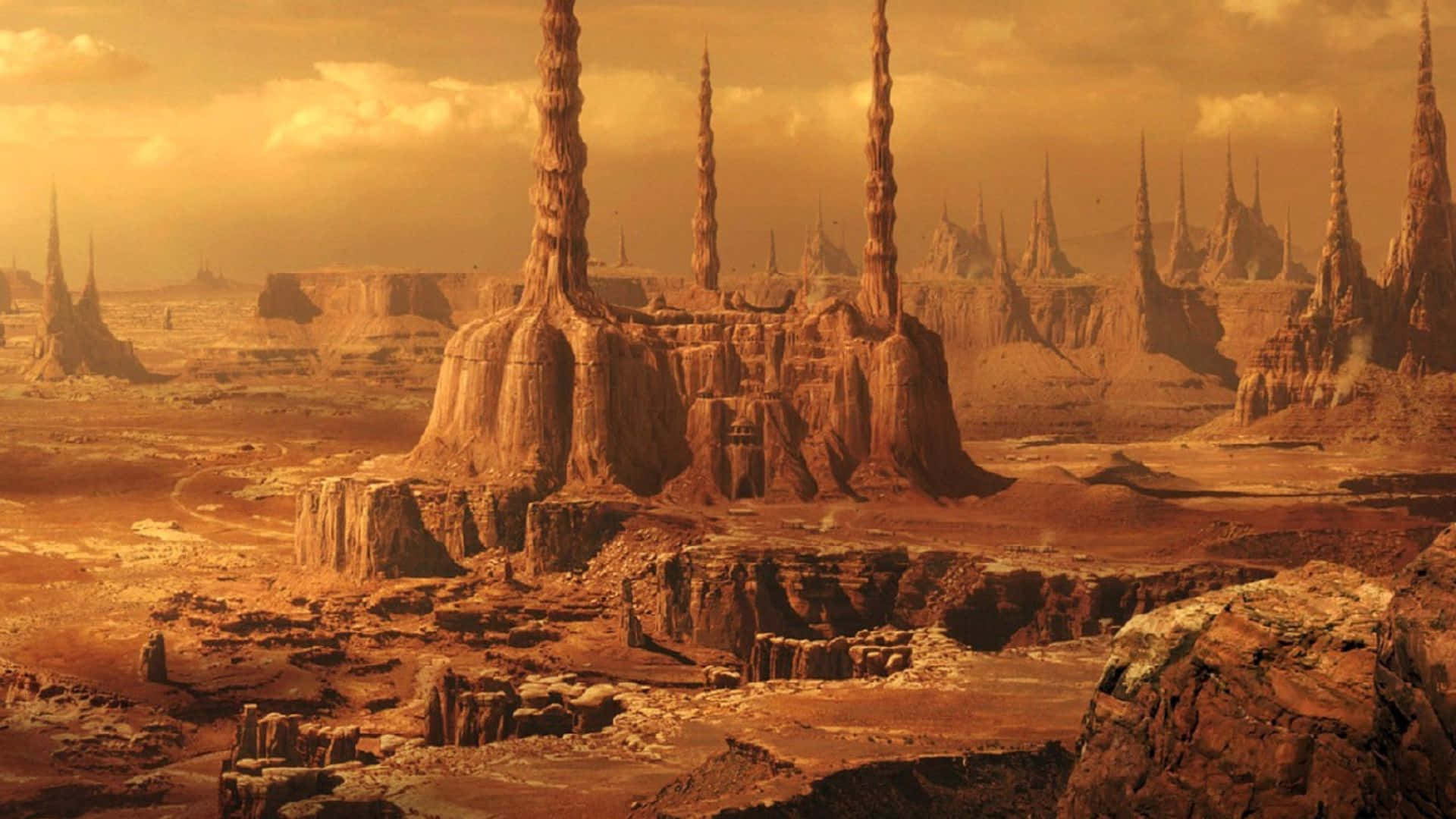 Geonosis 桌布 壁紙 — 一片廣闊的外星沙漠，在朦朧的金色天空下聳立著橙色的岩石尖塔。