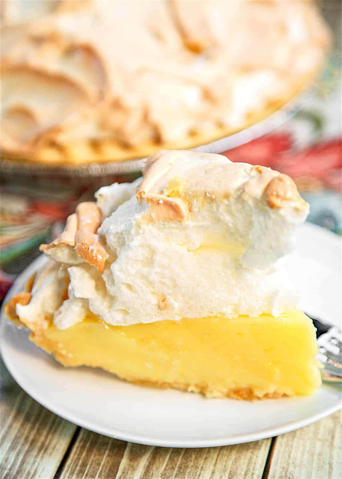 Meringue 桌布 壁紙 — 一片檸檬蛋白派，頂部烤至金黃，放在白色盤子上，置於質樸木桌上。