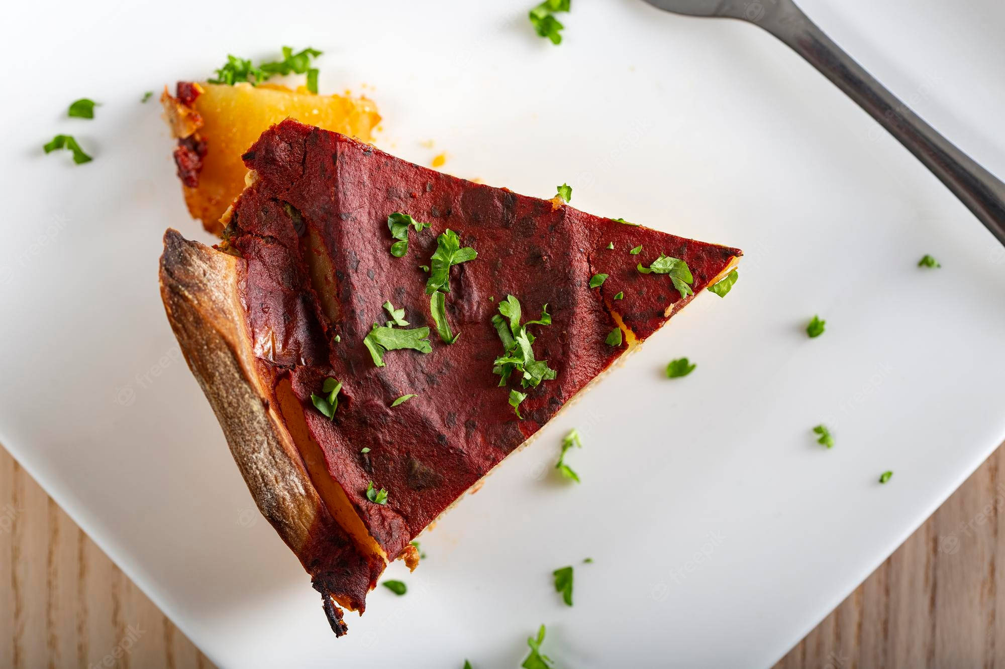 Food Photography 桌布 壁紙 — 一片深紅色甜菜根塔，金黃外皮，配以新鮮歐芹裝飾，放在白色盤子上。