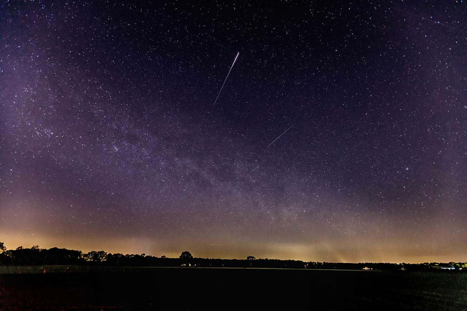 meteor 桌布 壁紙 — 一片漆黑的樹線上，兩顆明亮的流星劃過銀河，星空燦爛的夜空。