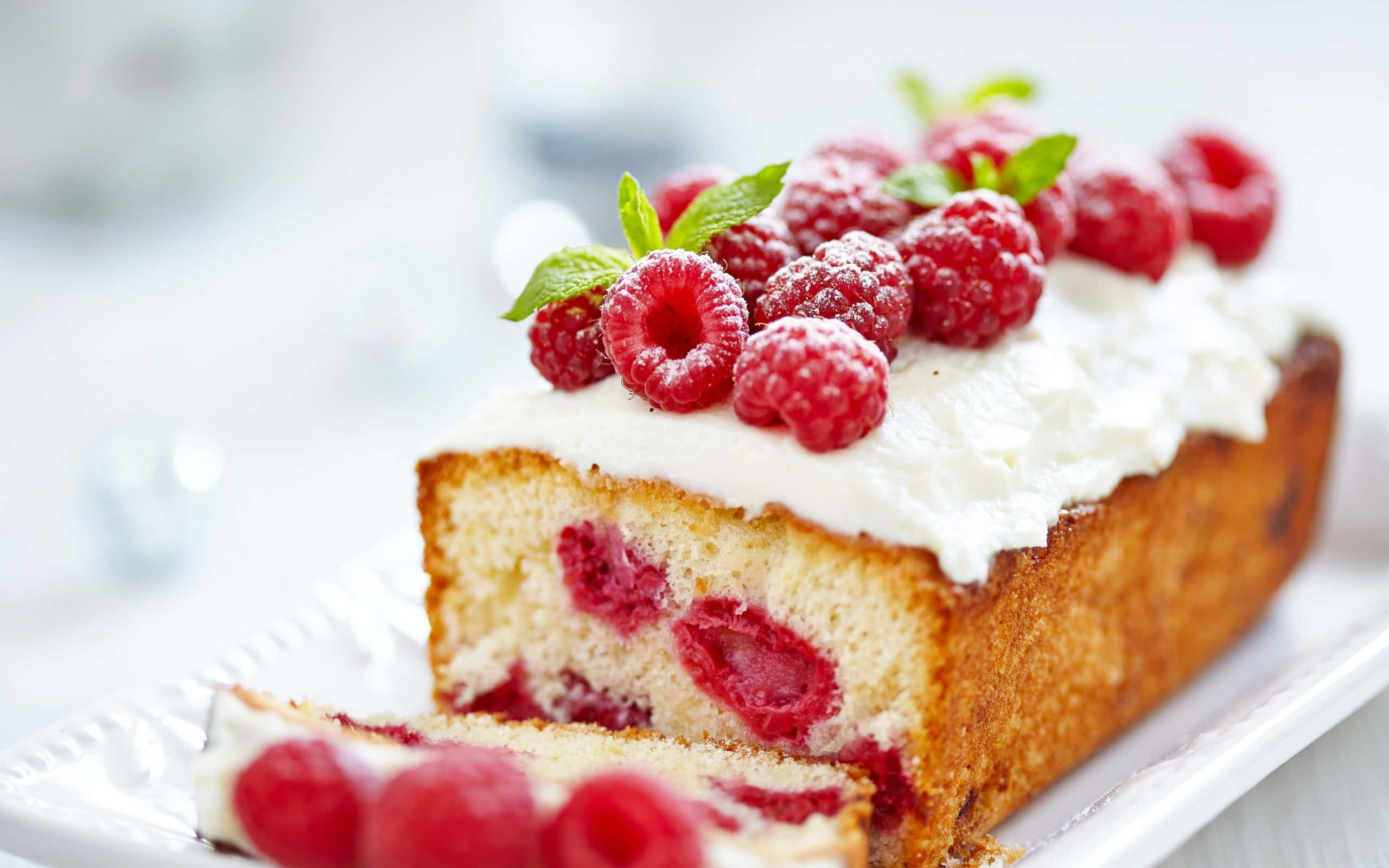 Spring Desserts 桌布 壁紙 — 一片濕潤的覆盆子蛋糕，上面放有鮮奶油和新鮮莓果，置於白色盤子上。