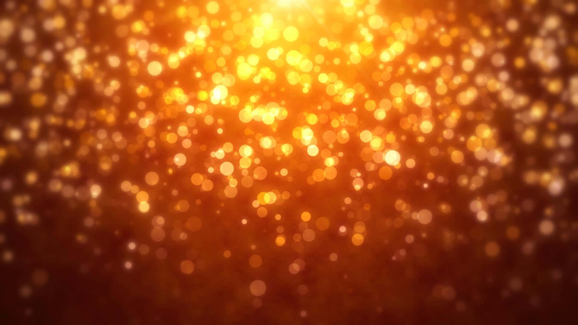 Orange Glitter 桌布 壁紙 — 一片燦爛的金色散景燈光，在深琥珀色背景下溫暖地發光。