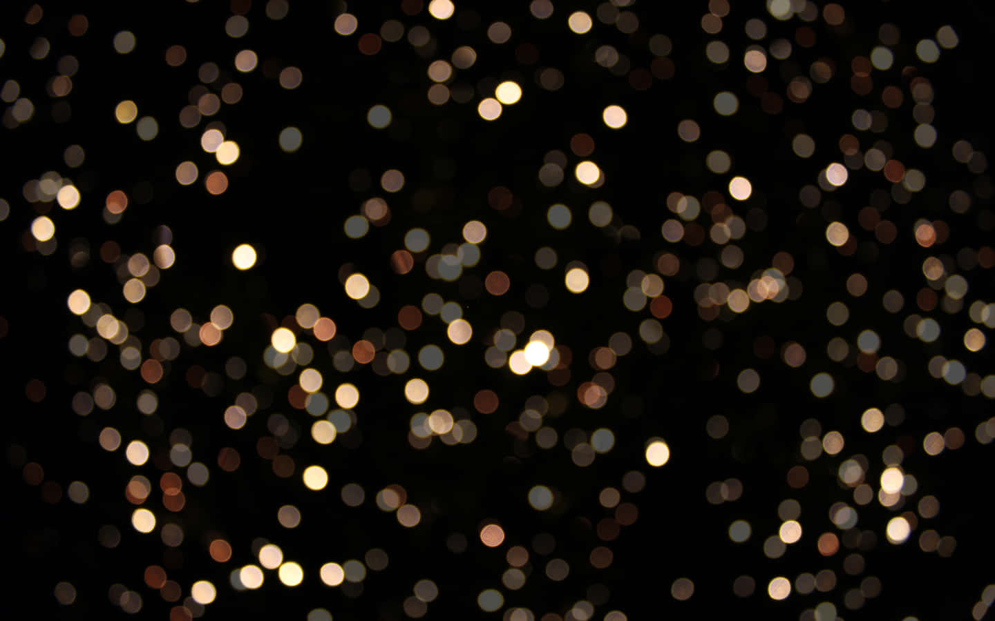 Bokeh 桌布 壁紙 — 一片發光的金色散景燈光散落在深黑色背景上，營造出夢幻的節日氛圍。
