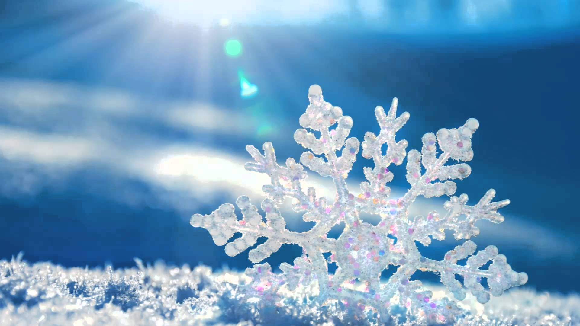 雪景 桌布 壁紙 — 一片精緻的雪花在明亮的陽光下，映襯著充滿活力的藍天，帶有鏡頭光暈閃爍。