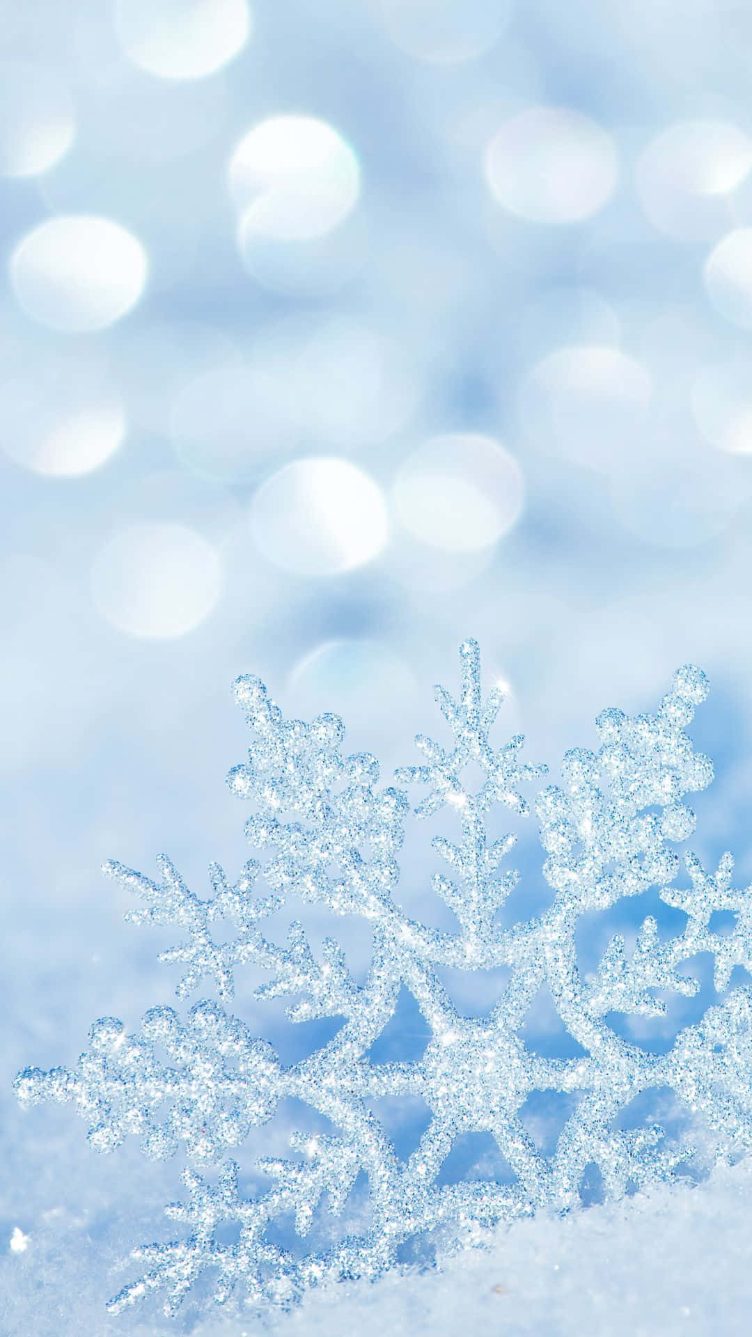雪 桌布 壁紙 — 一片精緻閃爍的雪花落在雪地上，背景是柔和的藍色散景。