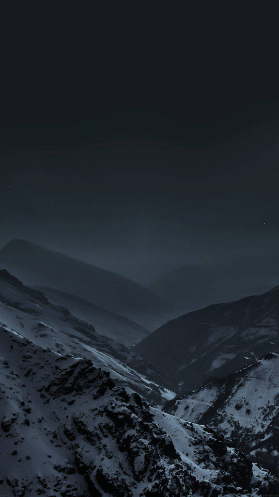 iPhone 動態 桌布 壁紙 — 一片荒涼的積雪山谷，在黑暗的星空下，瀰漫著霧氣般的氛圍。
