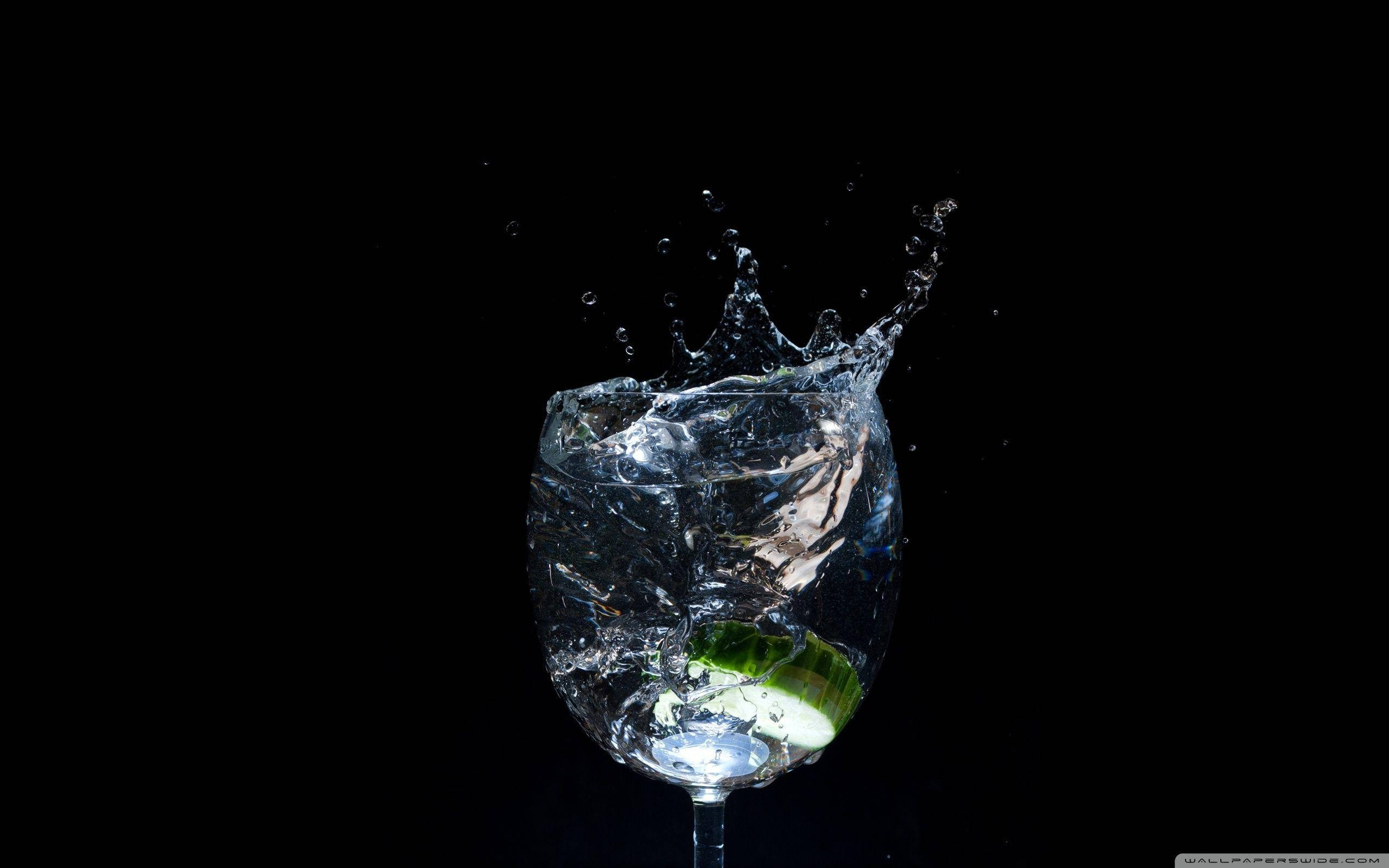 drinks 桌布 壁紙 — 一片萊姆落入酒杯中，在黑色背景下造成清澈的水戲劇性地飛濺。