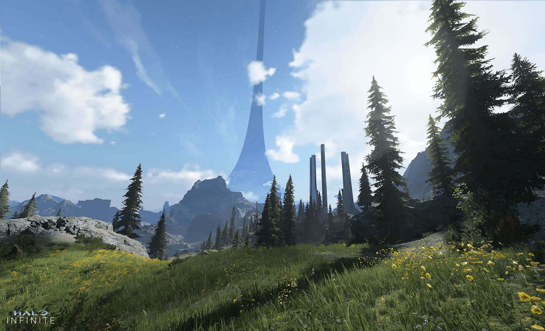 Halo Infinite 桌布 壁紙 — 一片長滿黃色花朵和松樹的草地，通向一座巨大的外星巨石和尖塔，在明亮的藍天下聳立在岩石山脈之上。