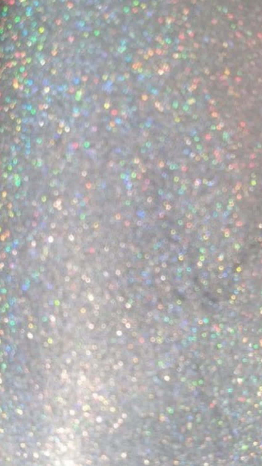 Silver Aesthetic iPhone 桌布 壁紙 — 一片閃爍的多彩亮粉顆粒在柔和的灰色背景上捕捉光線。